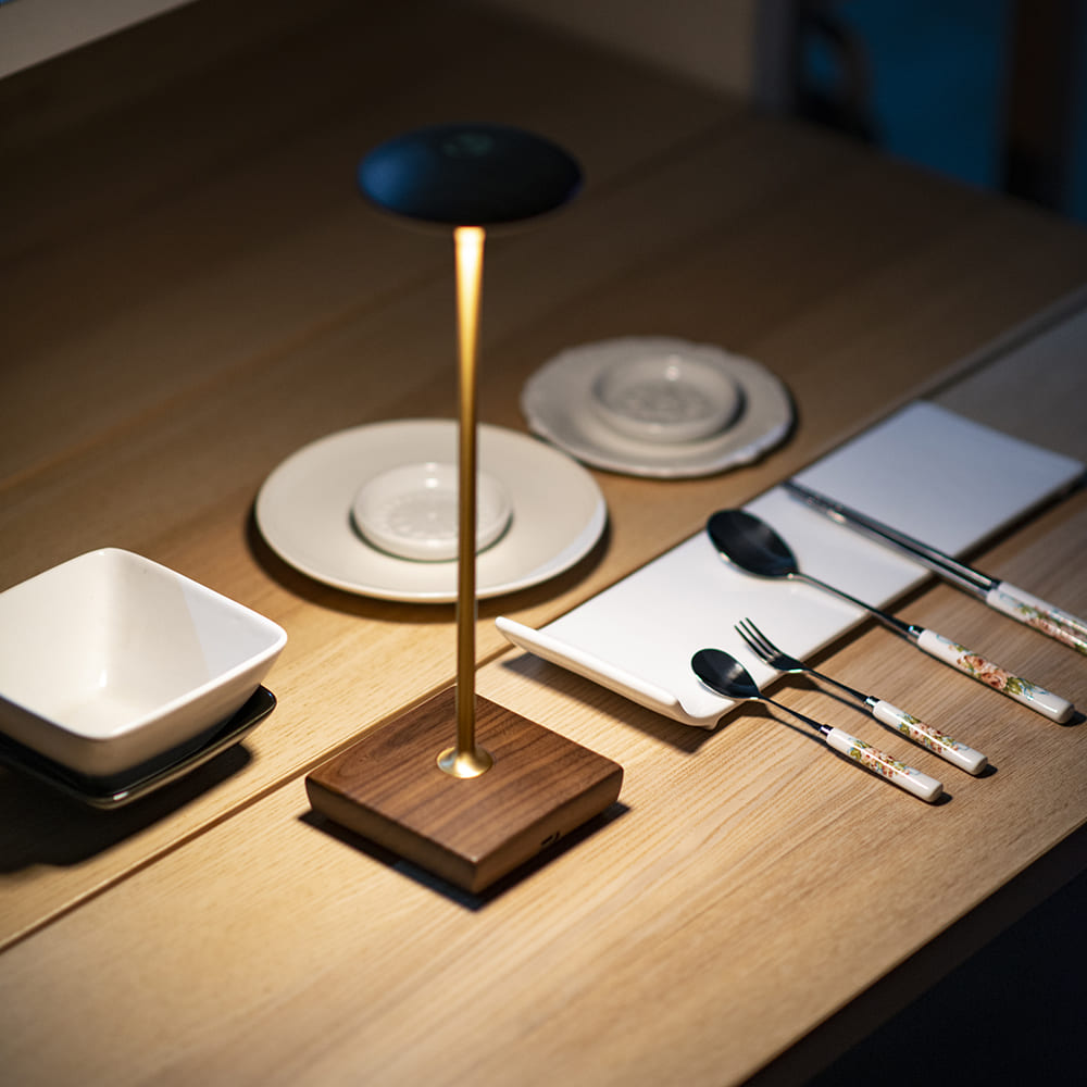 Cordless LED Table Lamp - A close-up shot of the square base design with a view of a cup and a red vase.
