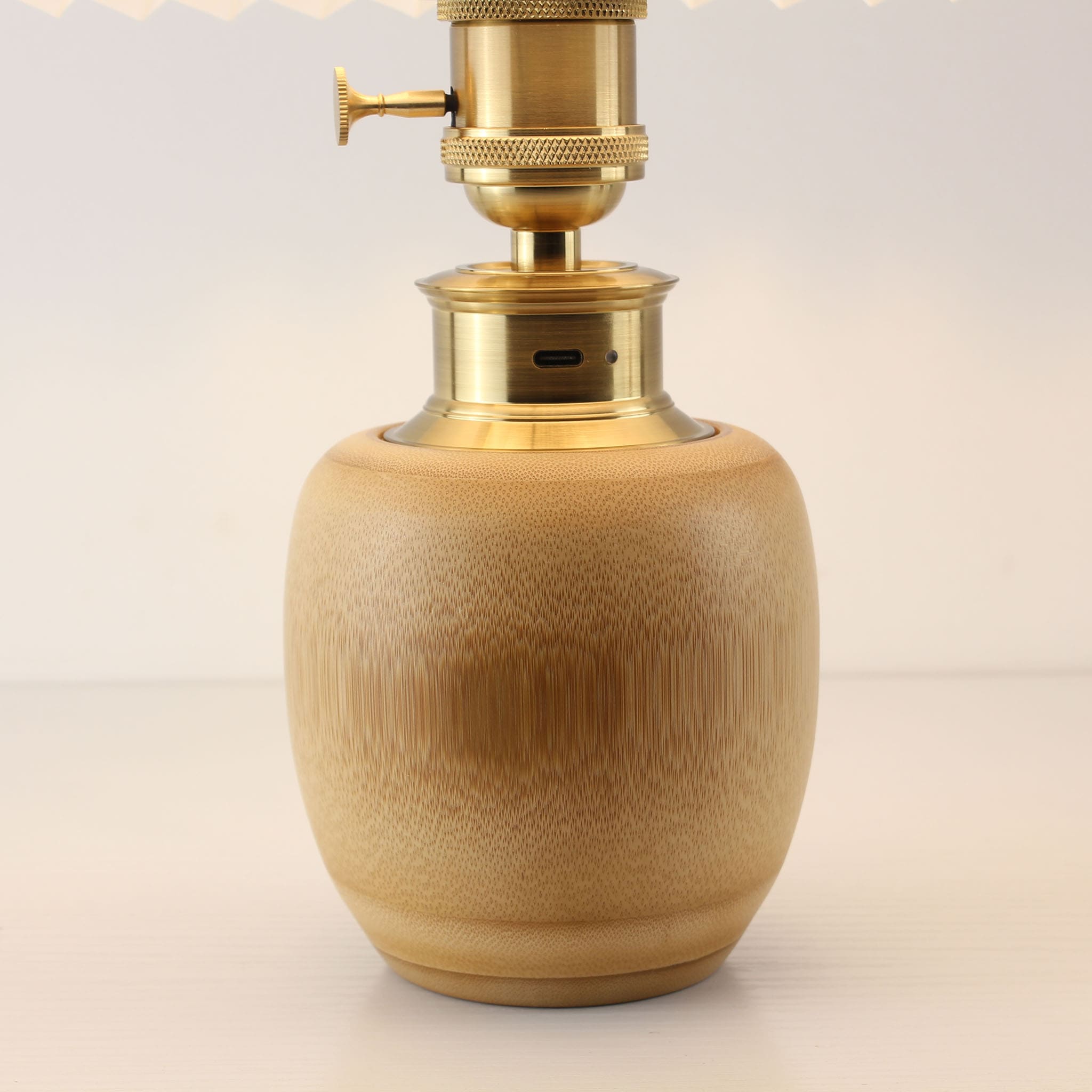 Close-up of the brass base and natural bamboo body featuring a built-in USB-C charging port for the rechargeable battery-powered lamp.
