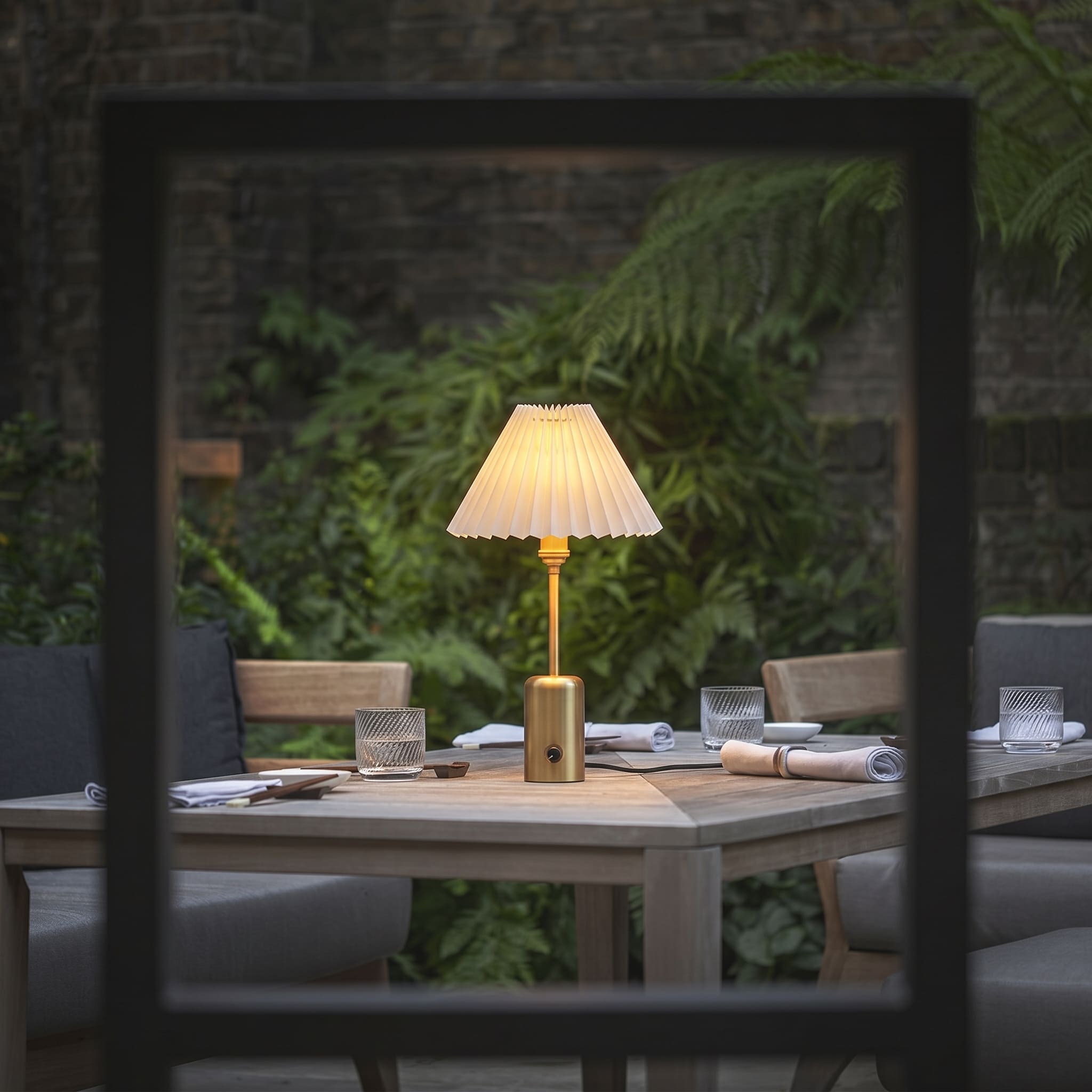Elegant brass cordless restaurant table lamp creating ambient outdoor dining lighting