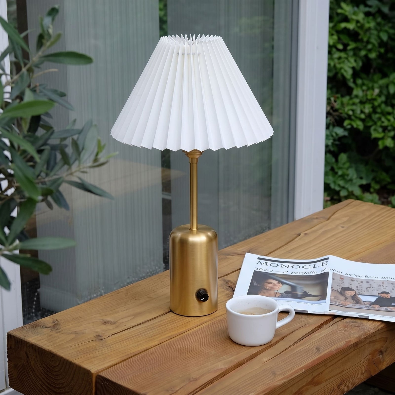 Brass cordless table lamp with a pleated lampshade on a living room table
