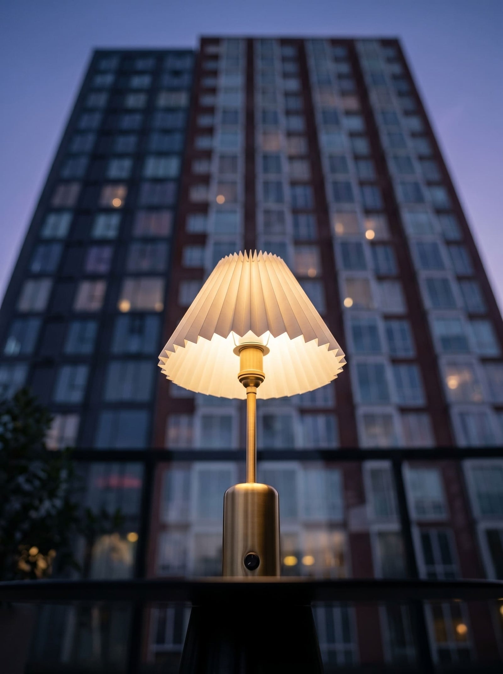 Brass cordless table lamp with a pleated lampshade on a patio table beside coffee and magazines