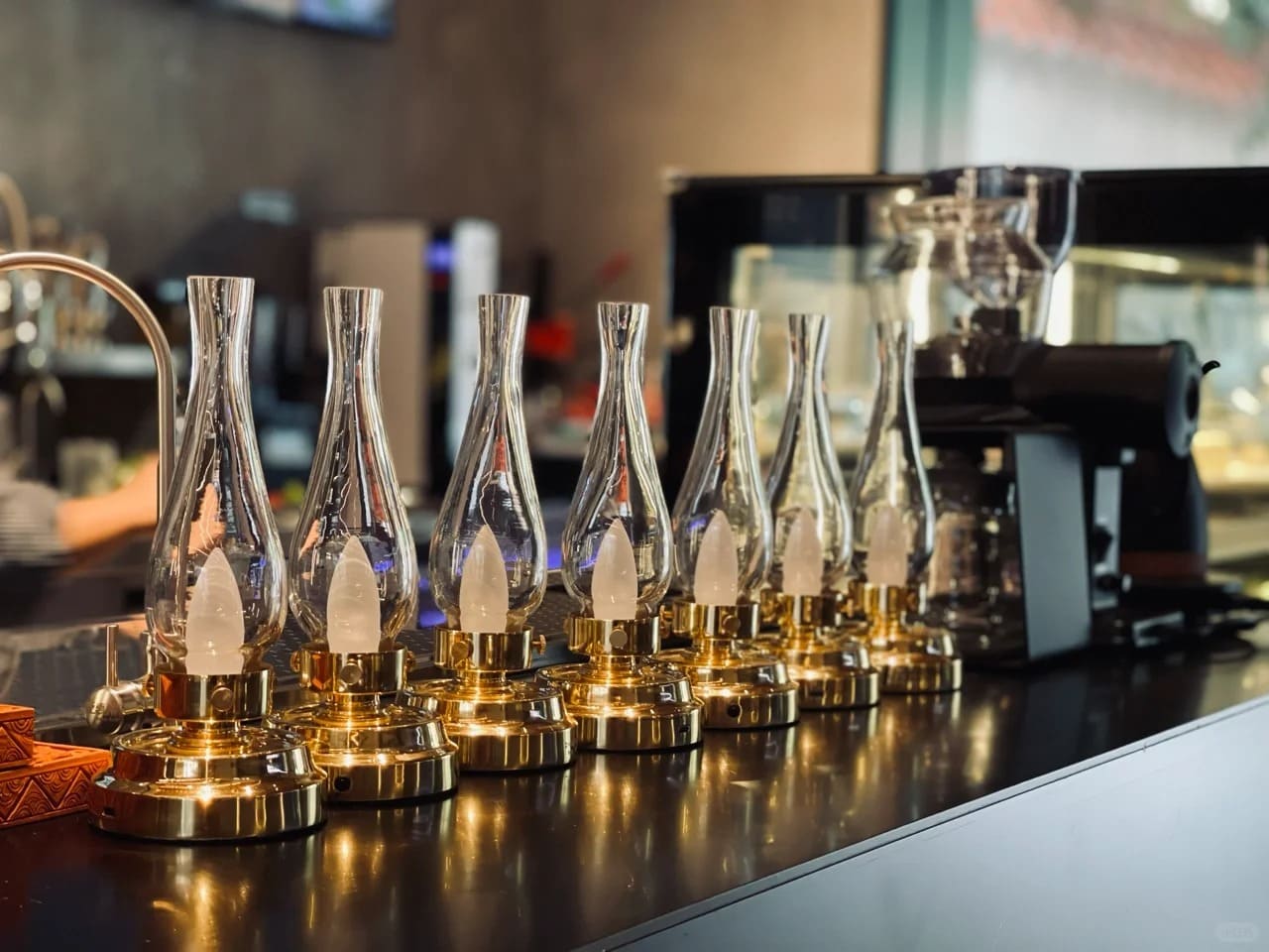 Brass LED oil lanterns creating warm ambiance along a cafe bar counter
