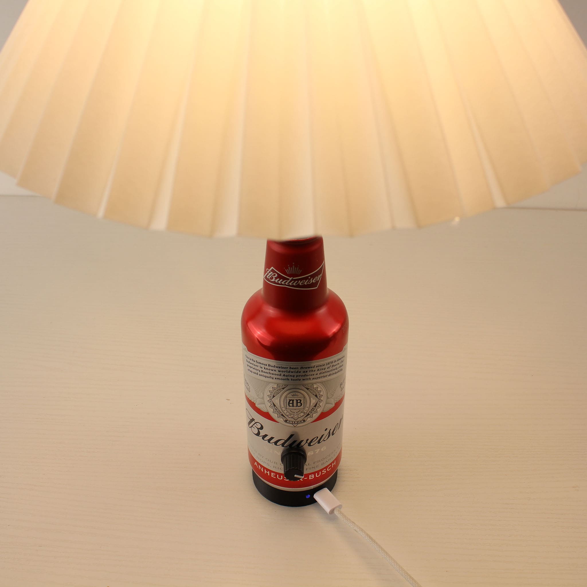 Close-up of the specialized magnetic charging port and Type-C cable at the base of the Budweiser bottle lamp