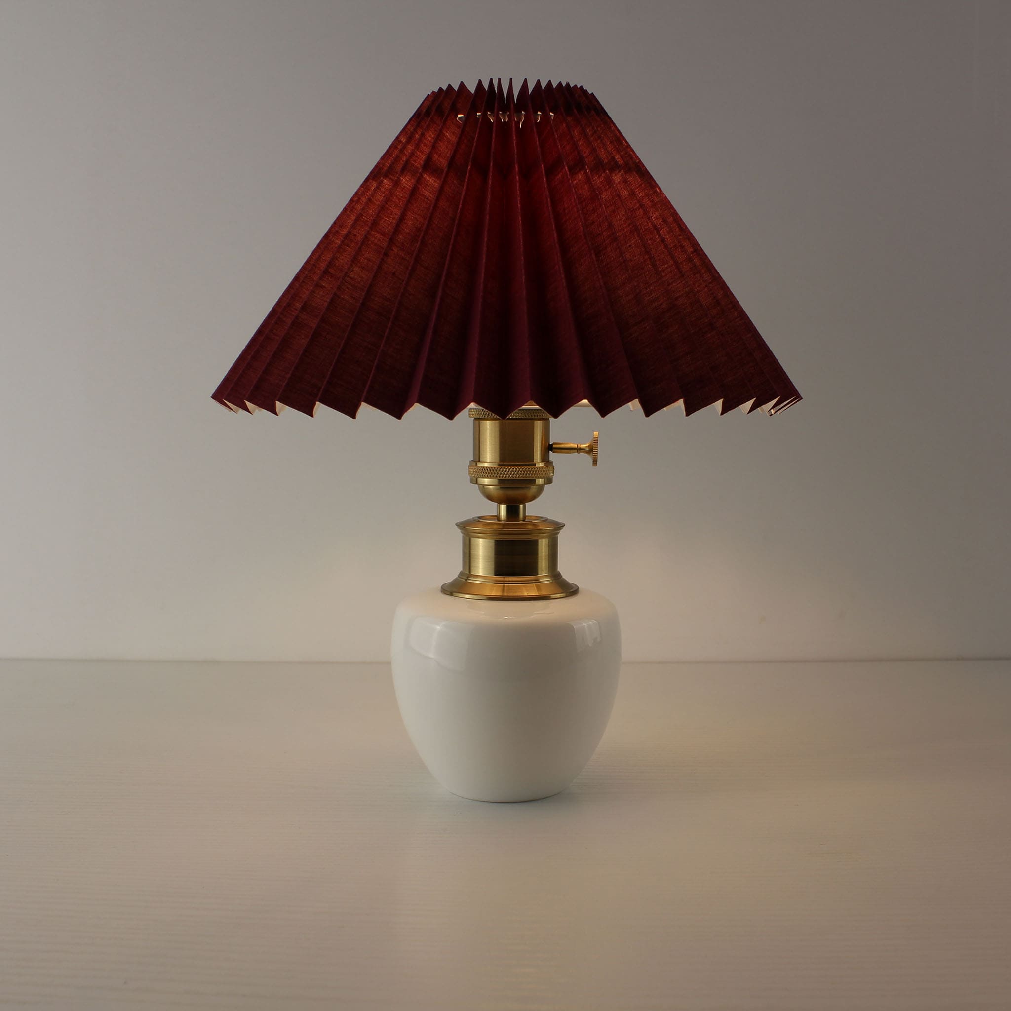 Sophisticated rechargeable table lamp with burgundy pleated shade, warm light aesthetic.