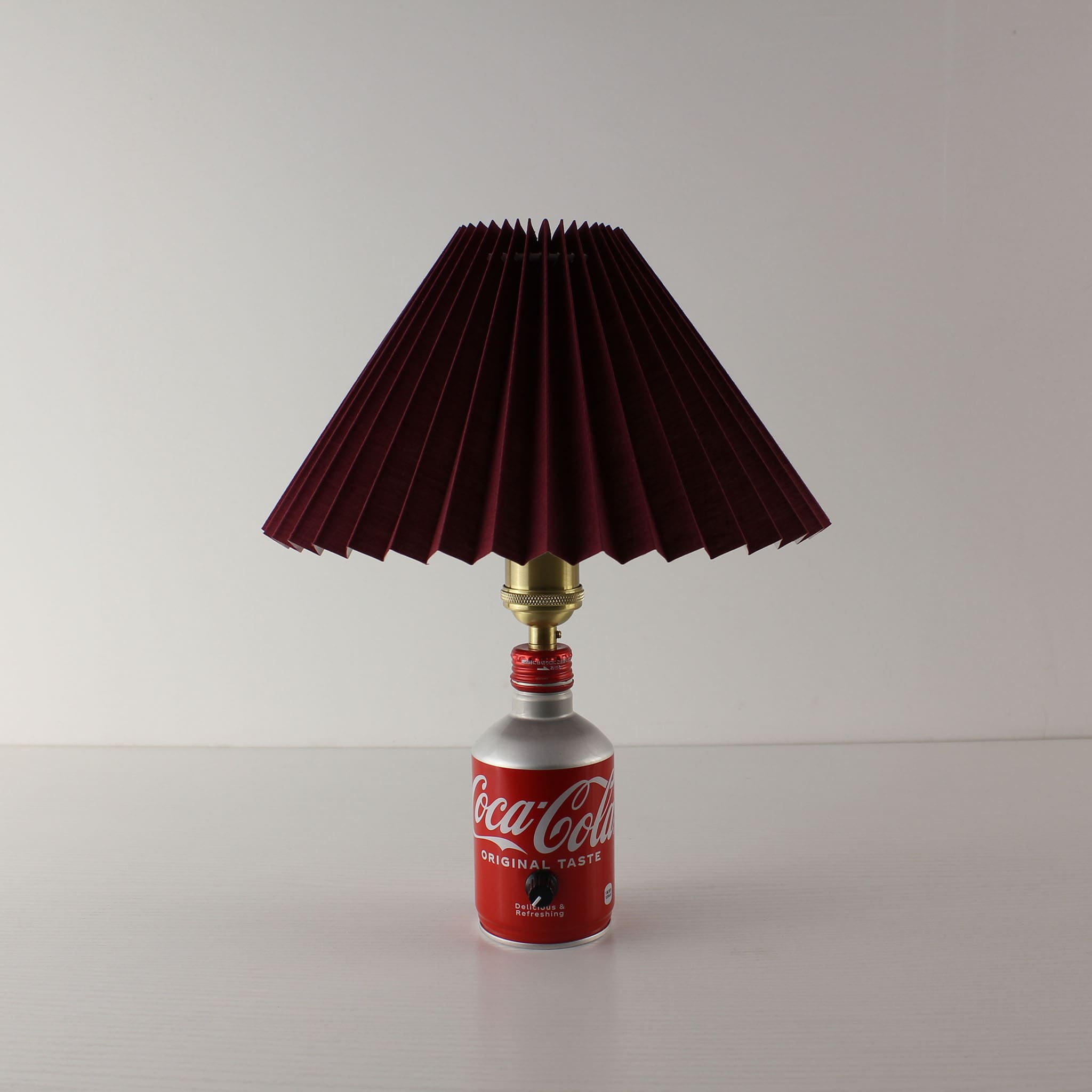 Side profile of the Coca-Cola aluminum bottle cordless lamp with a red shade, showing its sleek industrial design.