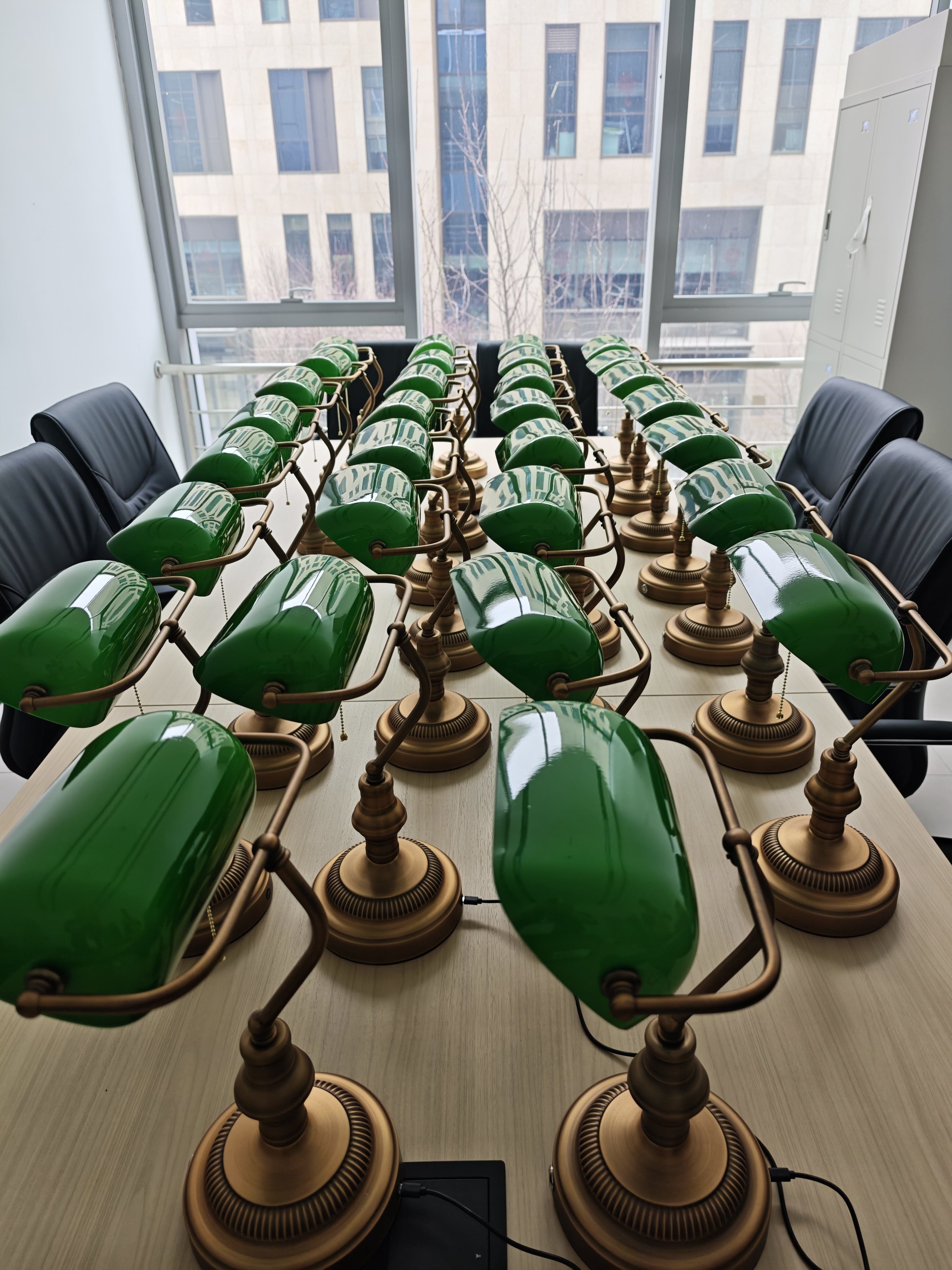Multiple cordless bankers lamps arranged on a conference table for commercial office lighting