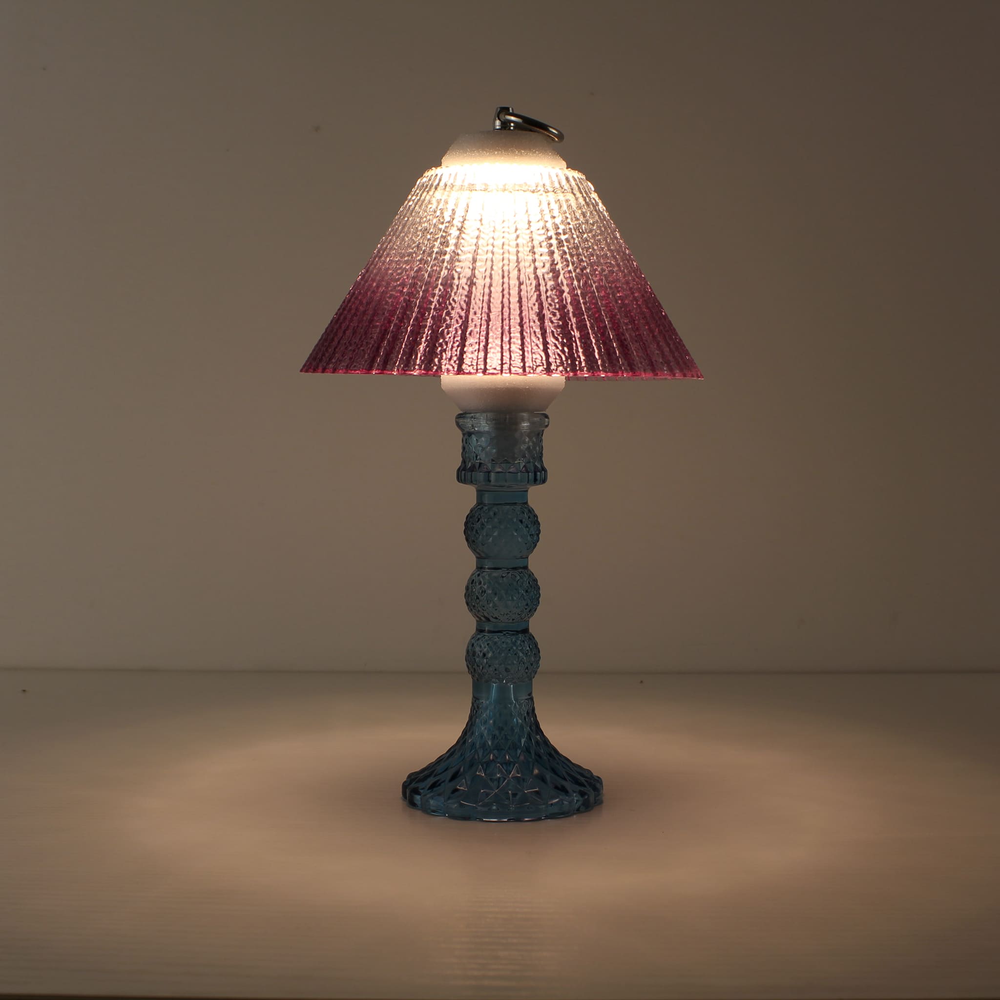 Decorative battery-powered table lamp (ON) with blue glass base and warm purple gradient shade for a mystical prismatic ambiance.