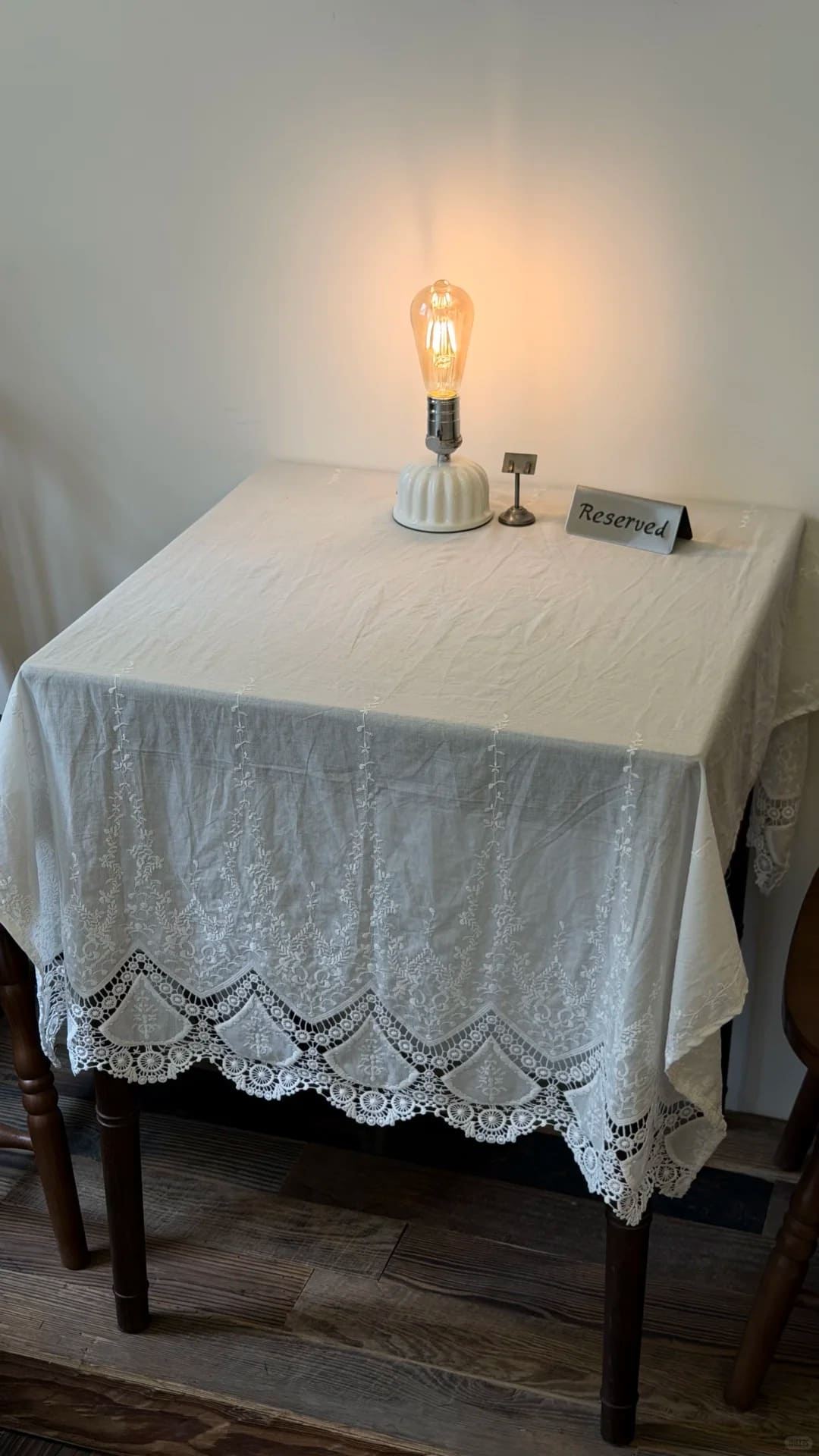 Cordless ceramic Edison bulb table lamp on a cafe table with white lace tablecloth and warm ambient lighting