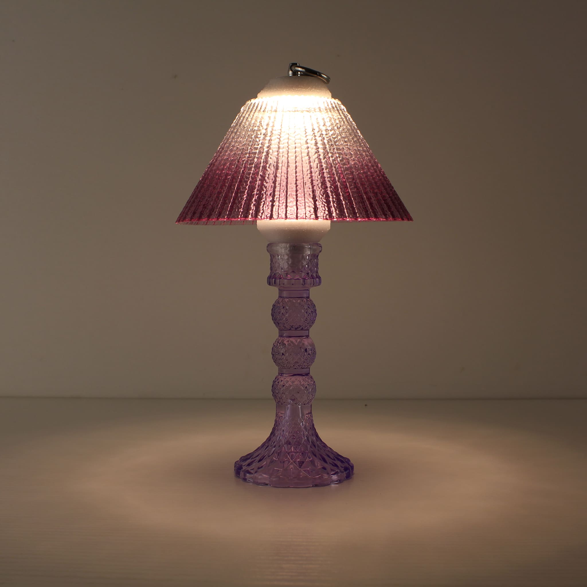 Decorative battery-powered table lamp (ON) with a cool purple glass base and warm purple gradient prismatic shade.