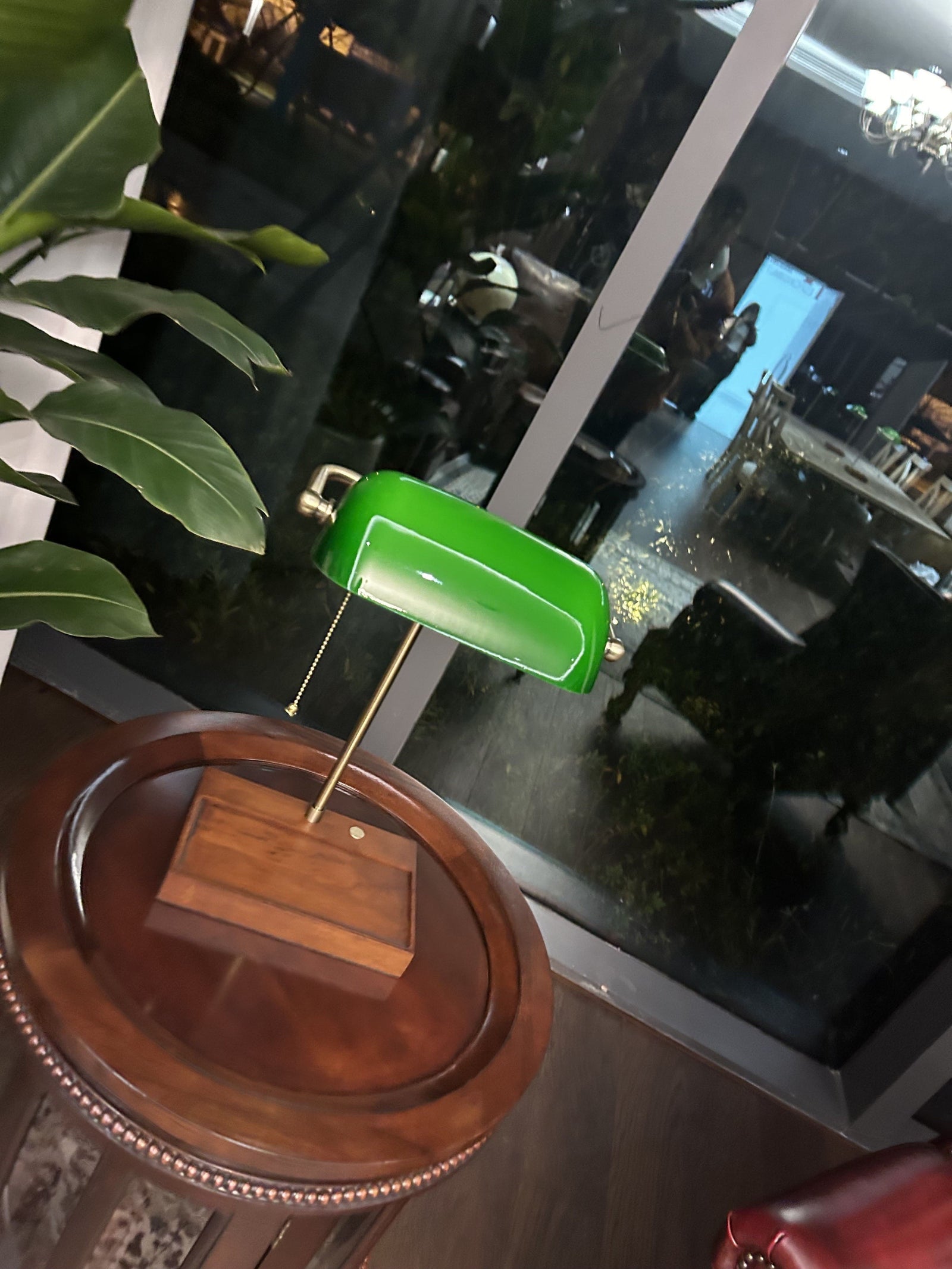Cordless green bankers lamp with wooden base placed on a round side table in an elegant evening interior