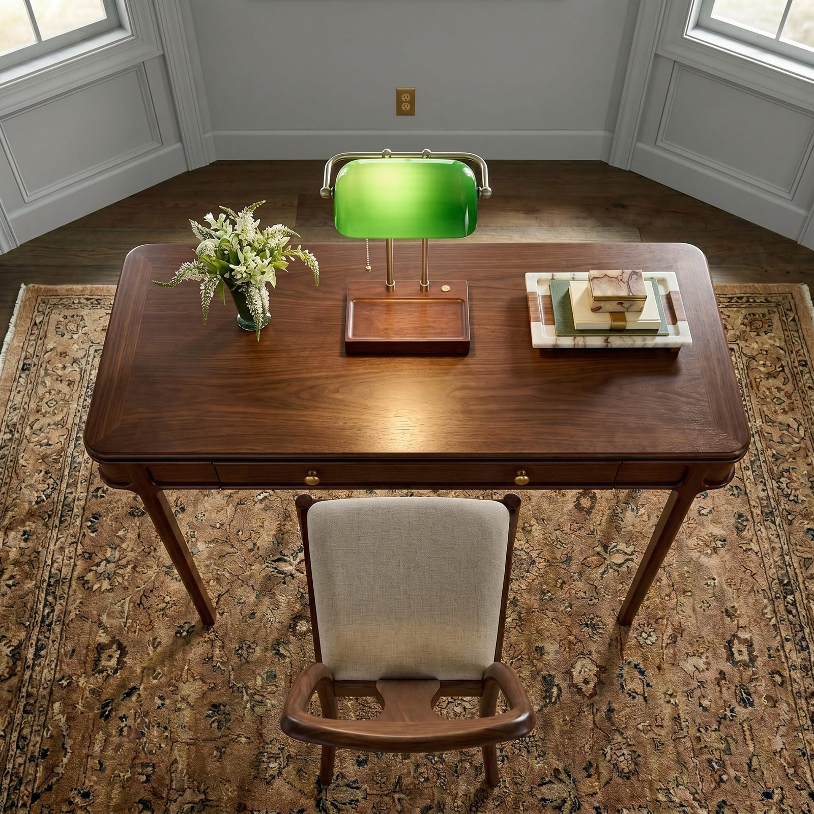 Cordless green bankers lamp with wooden base centered on a wooden writing desk viewed from above