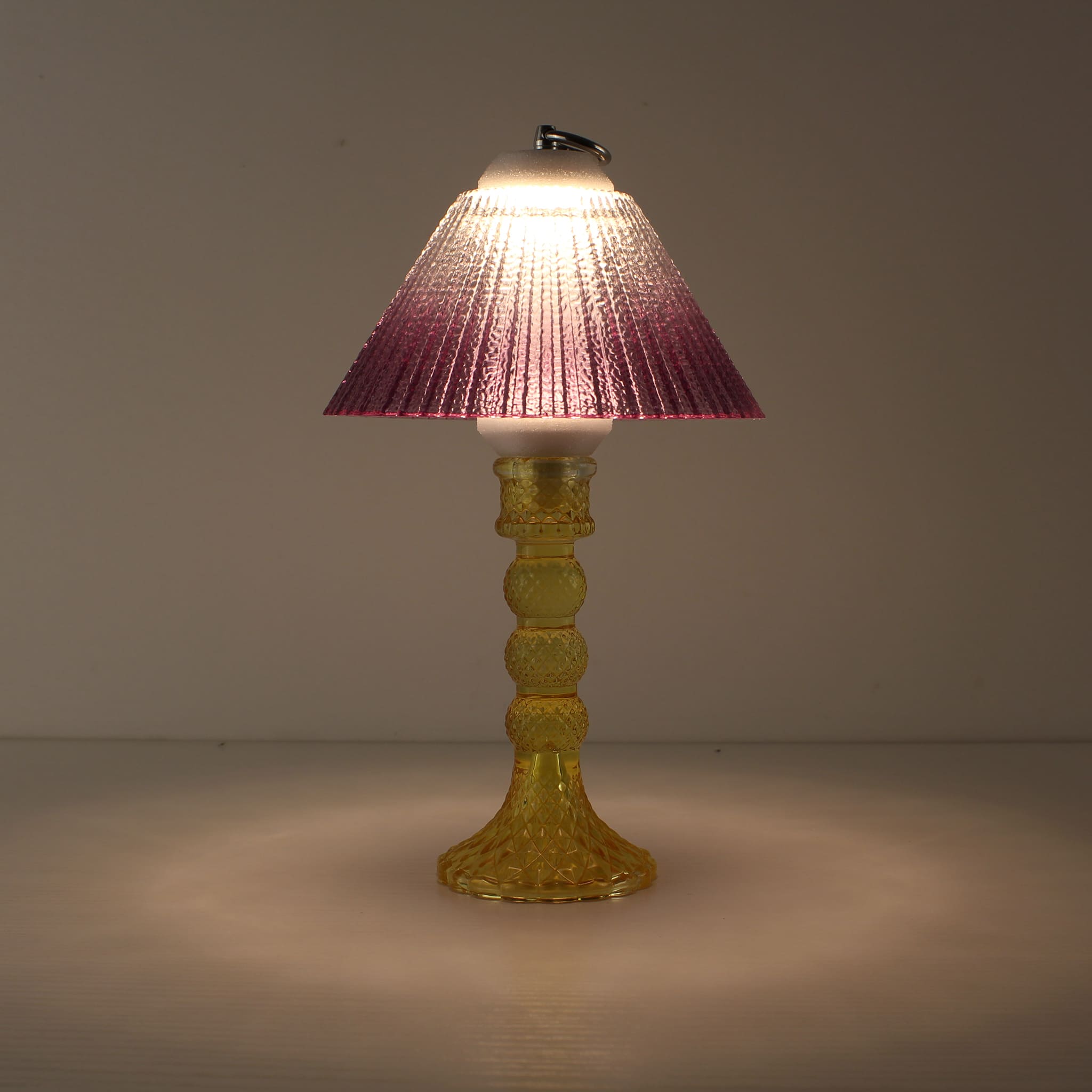 Decorative battery-powered table lamp (ON) with a yellow glass base and warm purple gradient prismatic shade.
