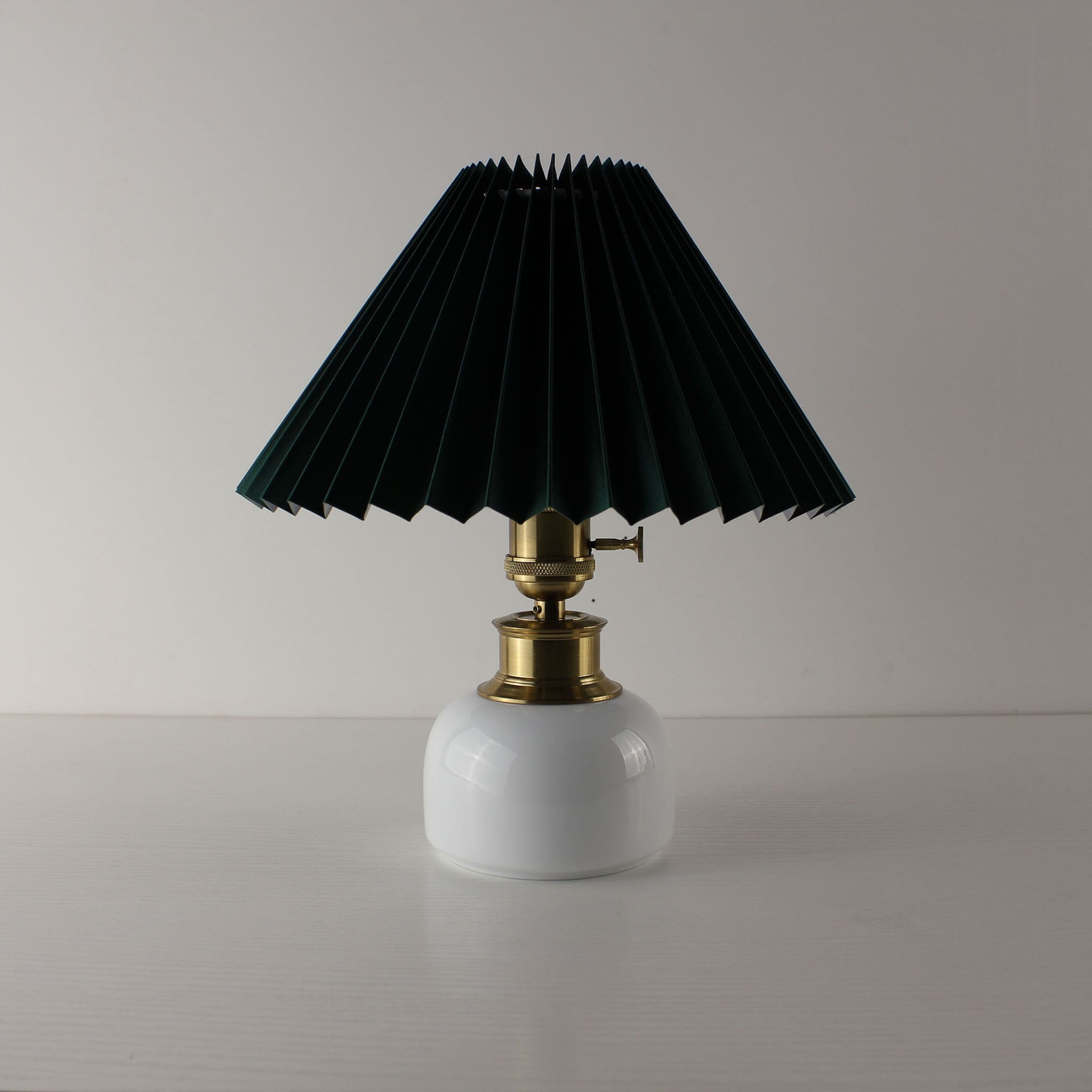 High-end ceramic cordless table lamp with a dark green pleated shade, luxury white porcelain base.