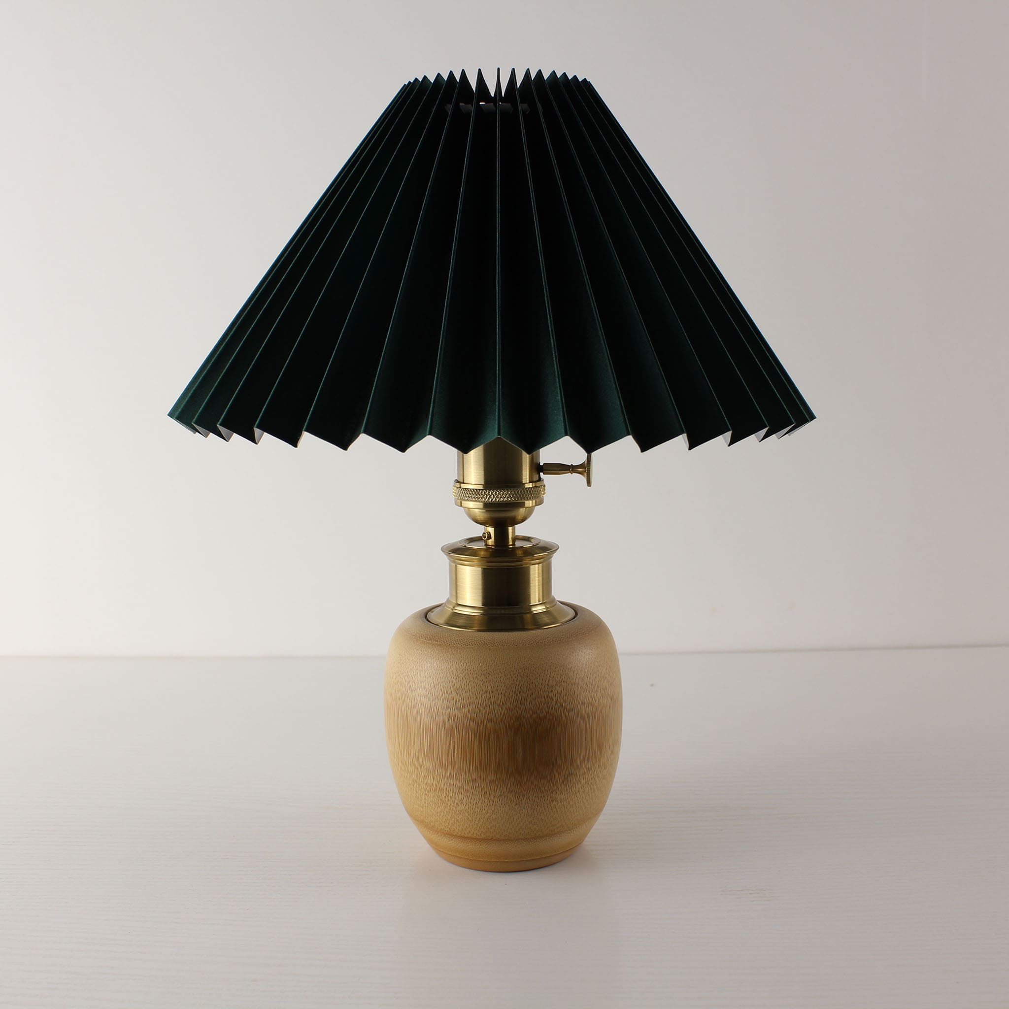 High-end emerald green pleated shade lamp with brass details and bamboo base, rechargeable cordless accent lighting.