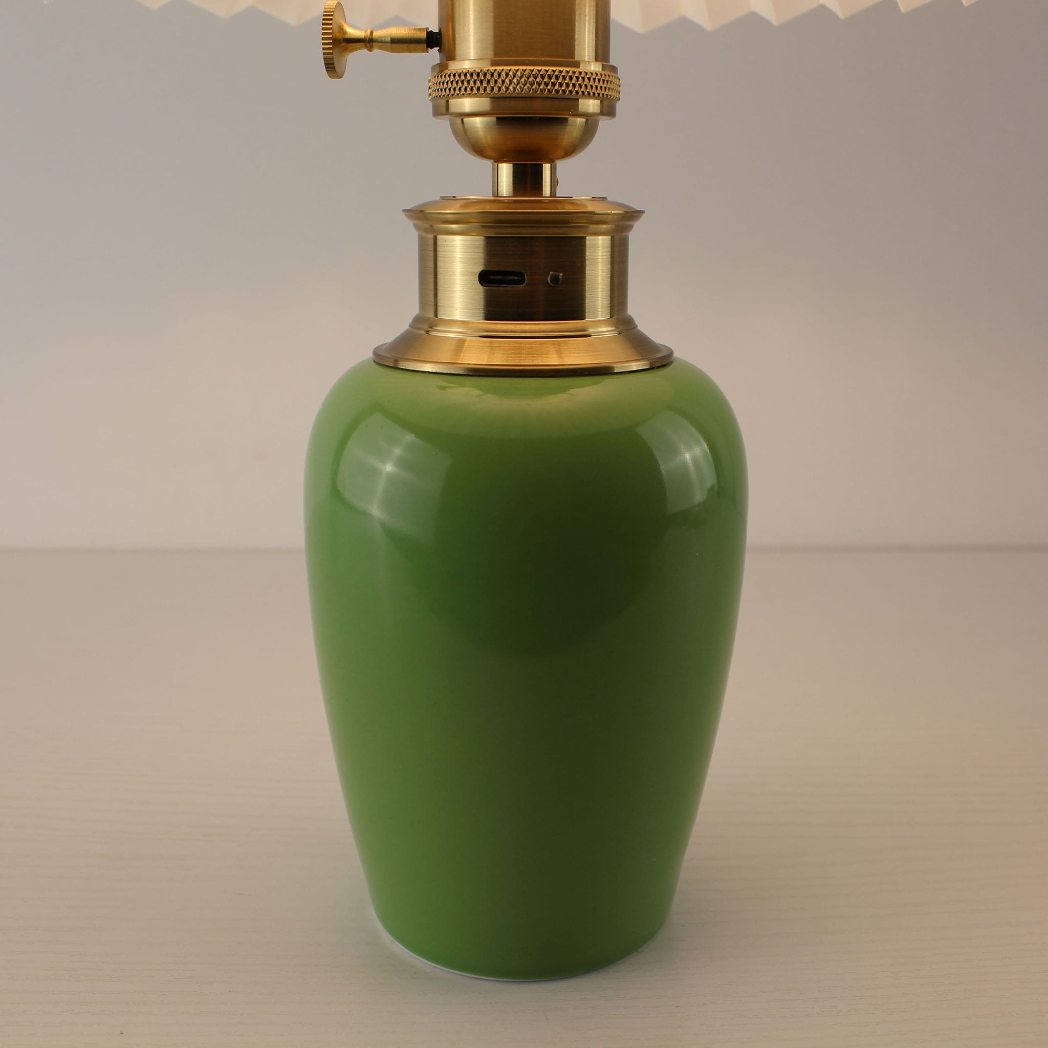 Close-up of the USB-C charging port and brass hardware on the green ceramic lamp base, highlighting its cordless and rechargeable technology.