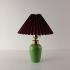 High-end green ceramic rechargeable table lamp with a dark red pleated shade, elegant restaurant decor.