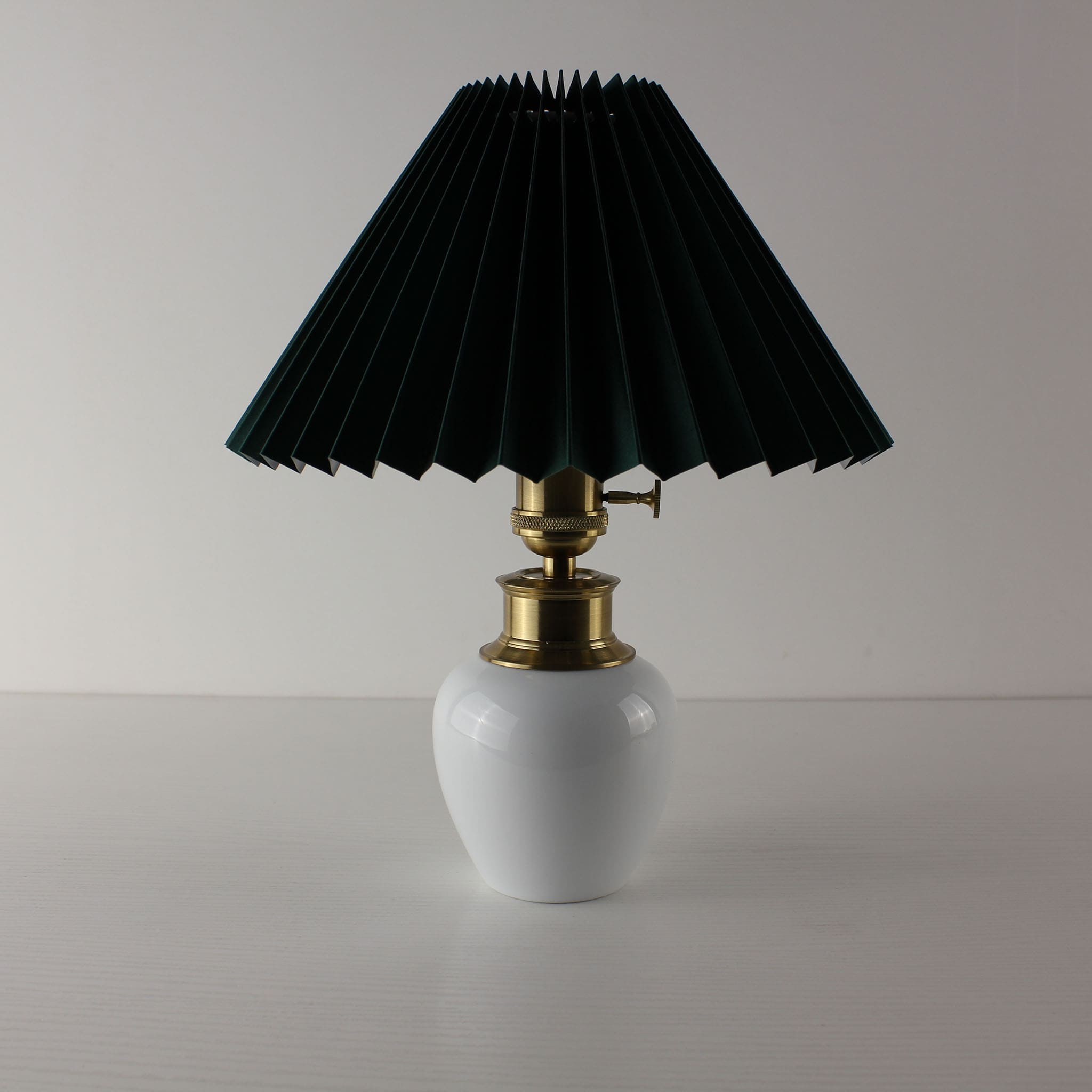 Mid-century modern white ceramic rechargeable lamp with a forest green pleated fabric shade.