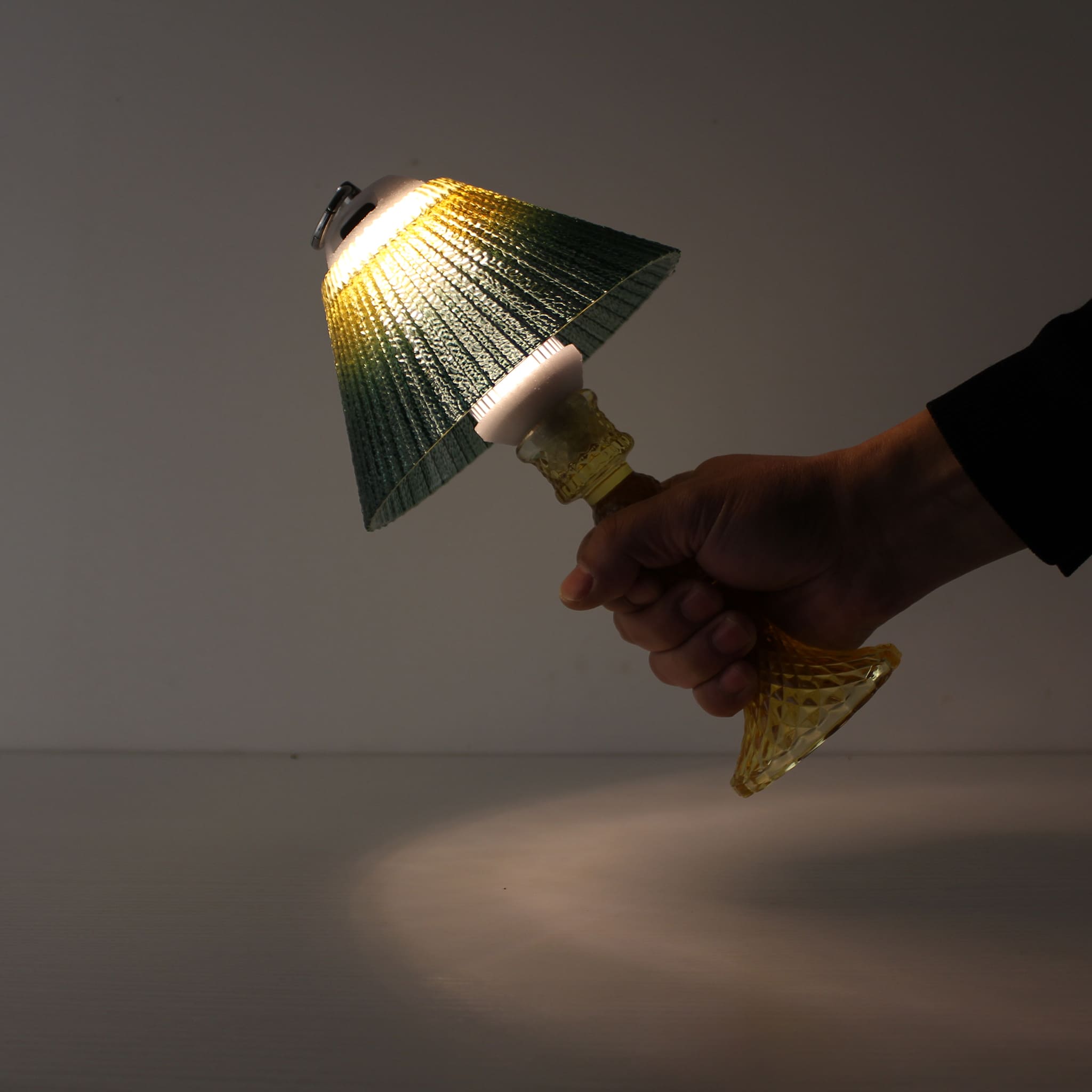 A hand holding the portable yellow lantern (ON) by its metal ring, demonstrating cordless mobility and 150h battery life.