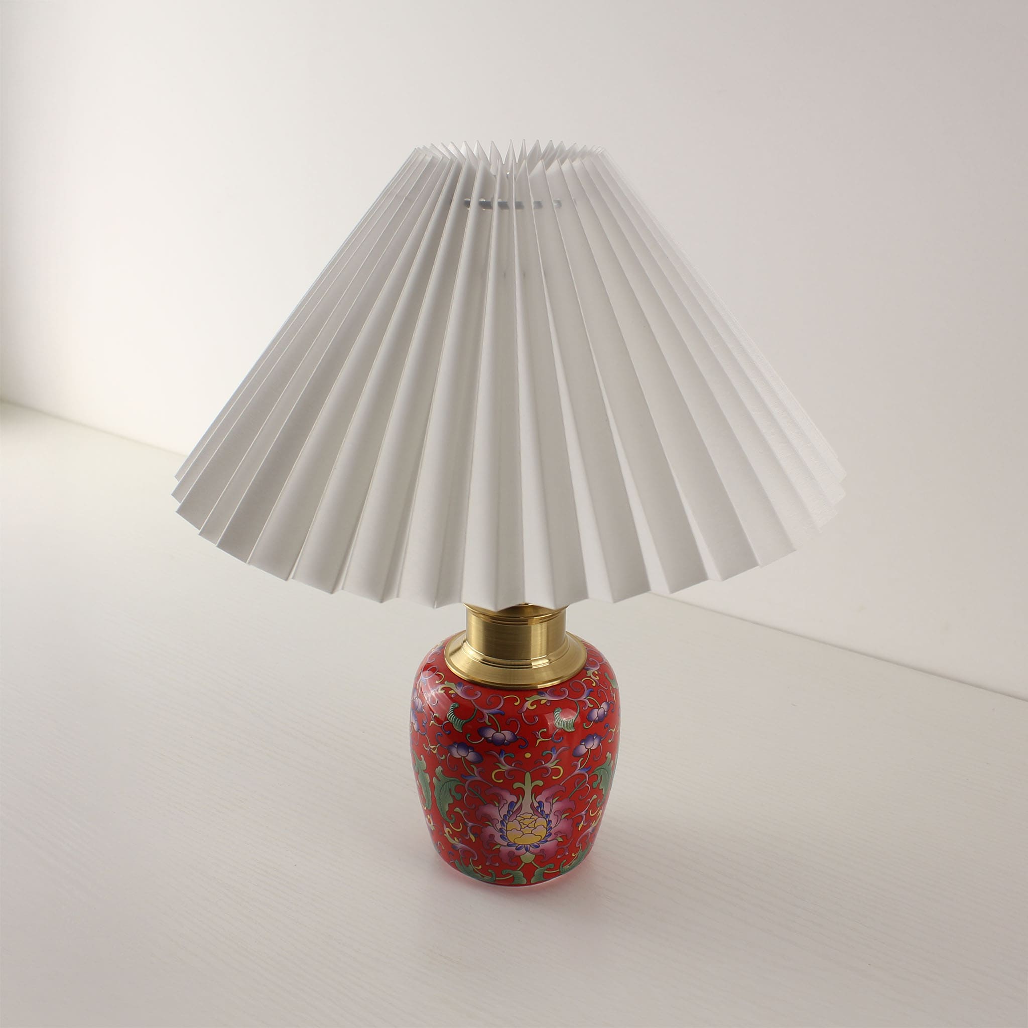 High-saturation red ceramic table lamp with a white pleated shade, featuring traditional Chinese enamel techniques and 3D textures