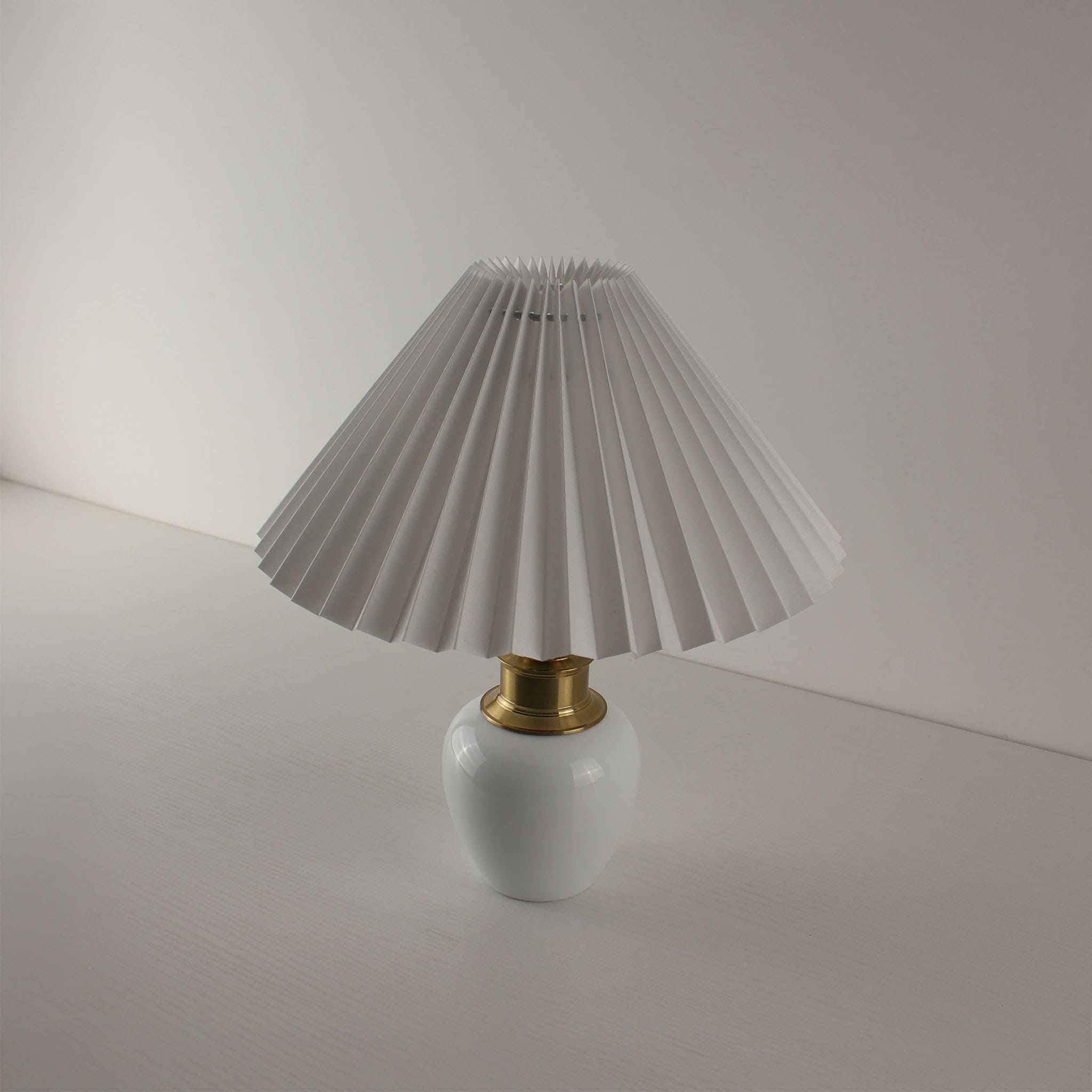 MCM style rechargeable white porcelain table lamp with pleated shade, viewed from a high angle.