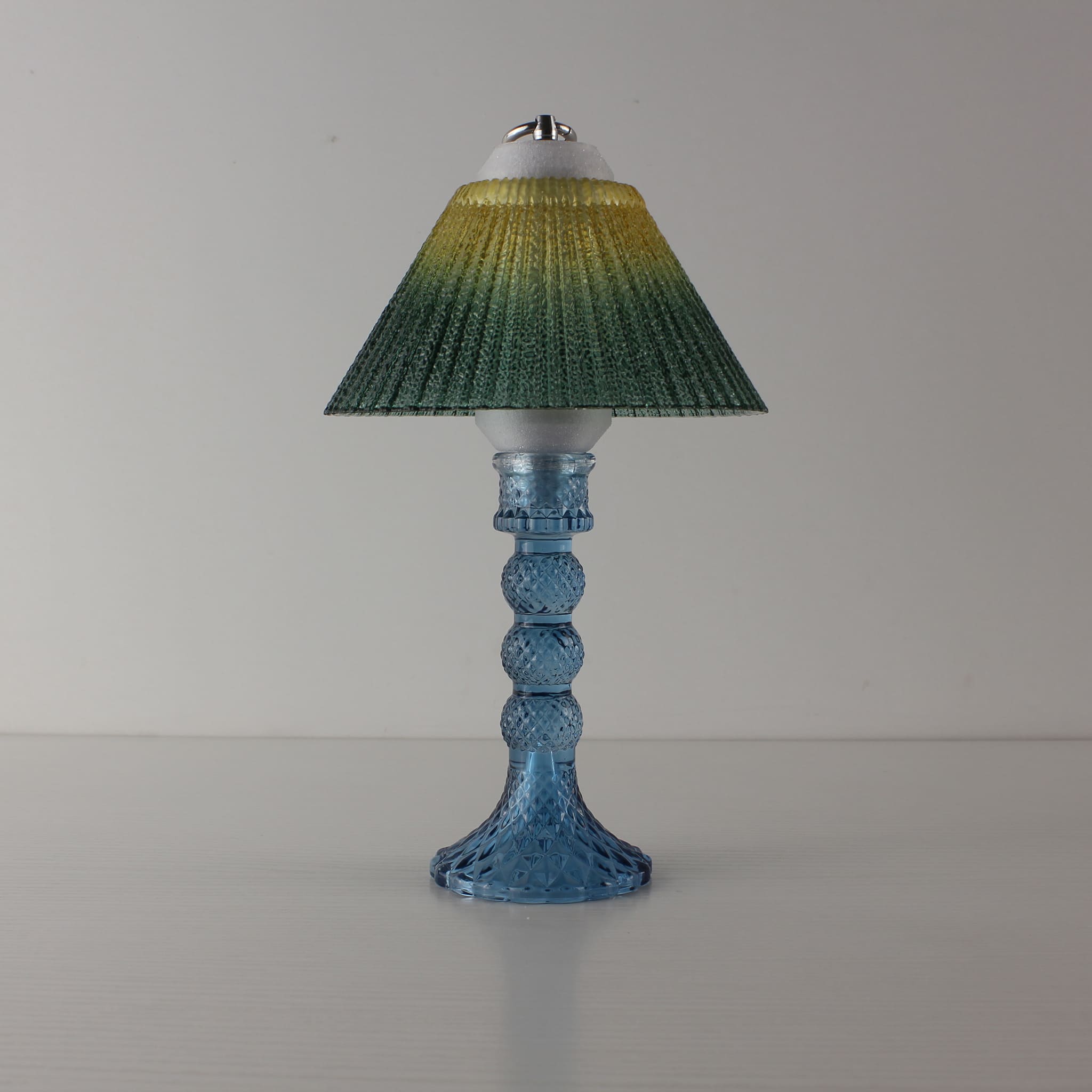 Minimalist blue table lamp (OFF) with yellow-to-green gradient shade, a perfect decorative object for modern interior design.