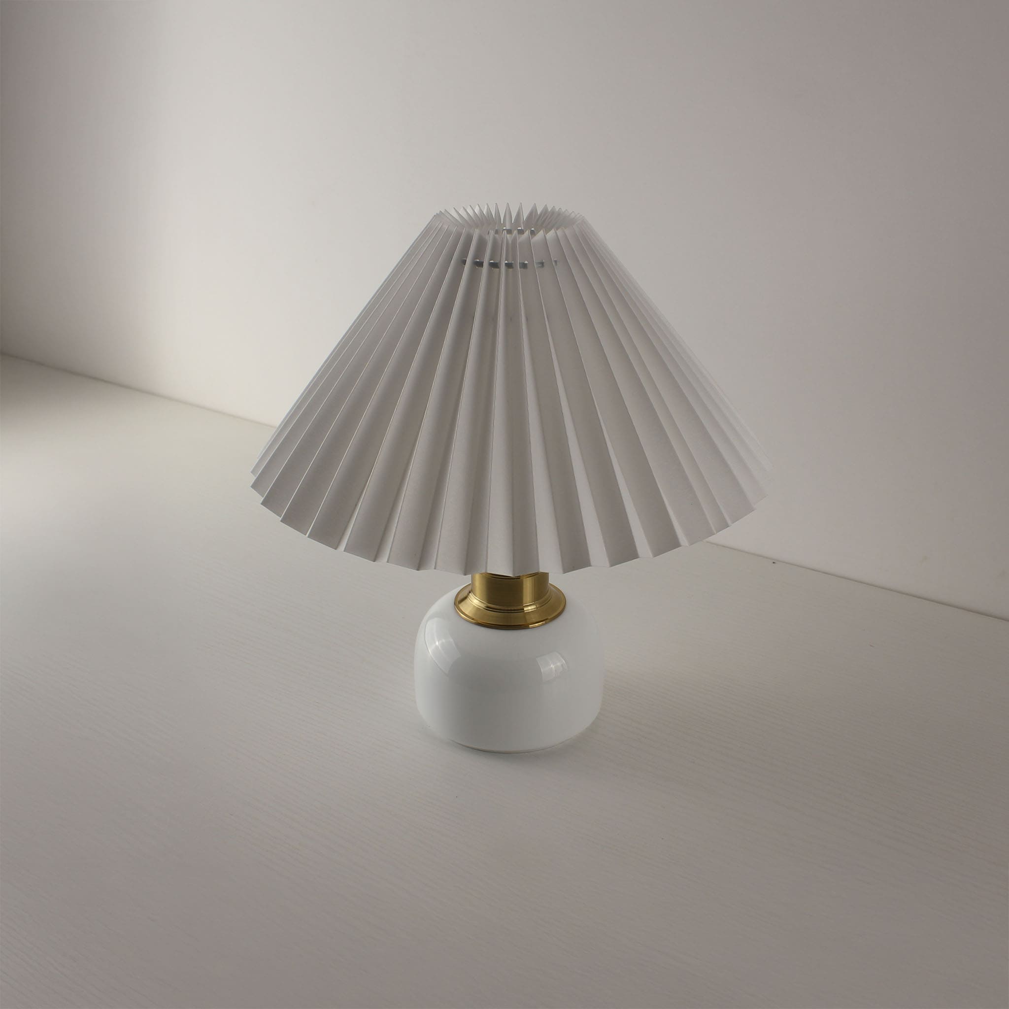 Minimalist rechargeable nightstand lamp with white pleated shade and luxury ceramic finish for home decor.
