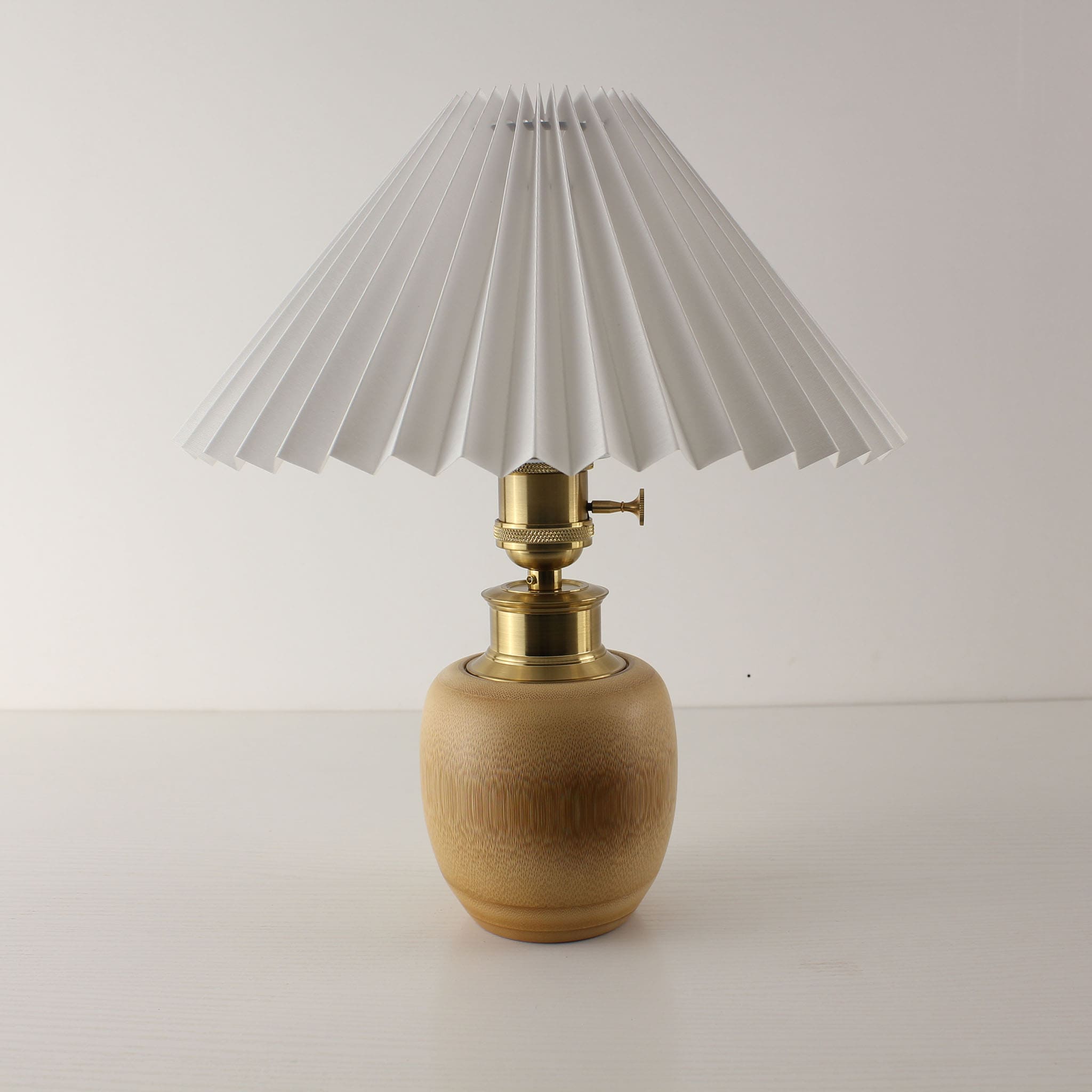 Minimalist white pleated shade lamp with natural bamboo base, battery operated cordless lighting for weddings and cafes.