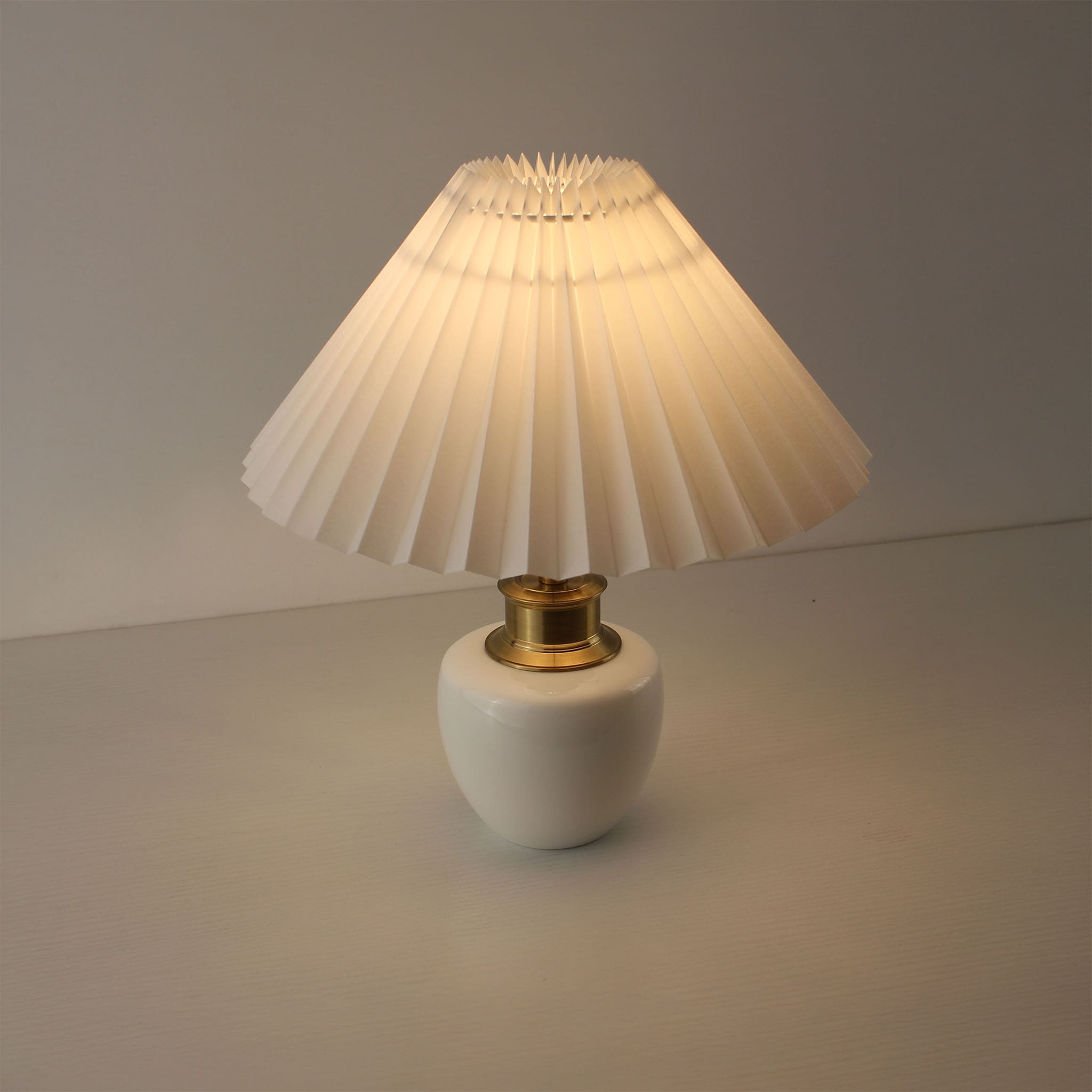 Mid-century modern white ceramic lamp with a warm light glow, suitable for luxury home decor.