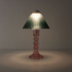 Moss green glass rechargeable lamp in a dark setting, illustrating the sunset-like atmosphere and prismatic light patterns for mood-focused bars.