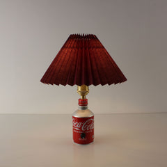 Handcrafted Japanese Coca-Cola bottle lamp with a burgundy red pleated shade illuminating a warm ambient glow.