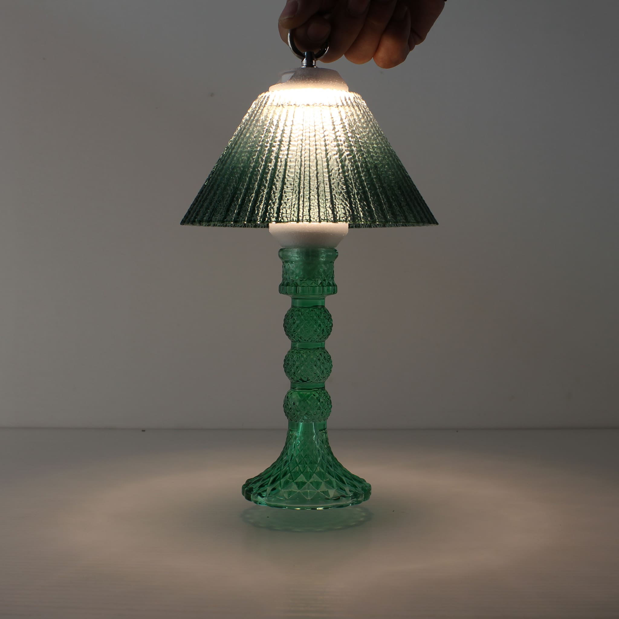 Hand holding the Prism portable lantern (ON), demonstrating cordless convenience and 3000K warm LED.