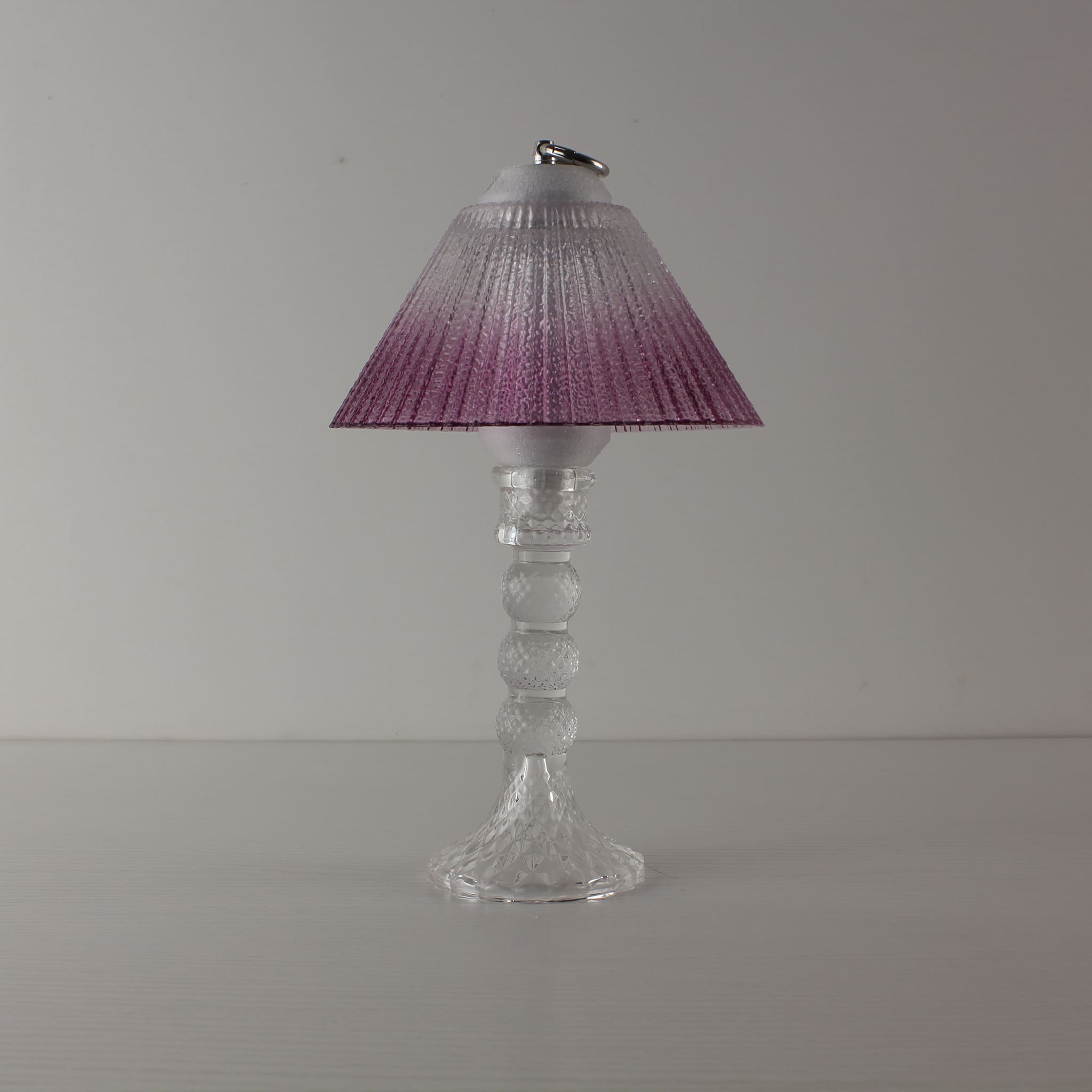 Decorative transparent glass lamp (OFF) with purple gradient shade, an elegant centerpiece for home decor.