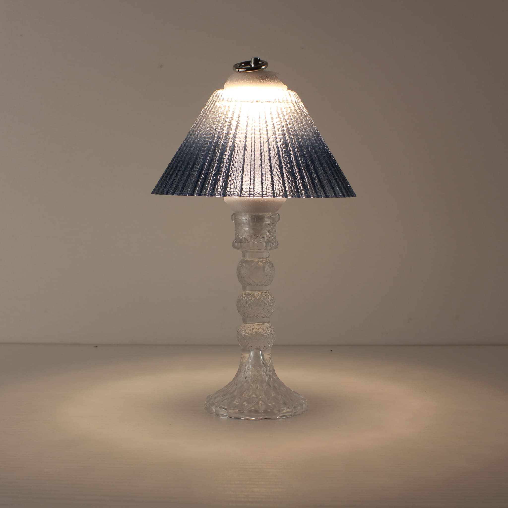 Prism rechargeable lantern (ON) with clear faceted base and blue gradient shade emitting a soft prismatic glow.