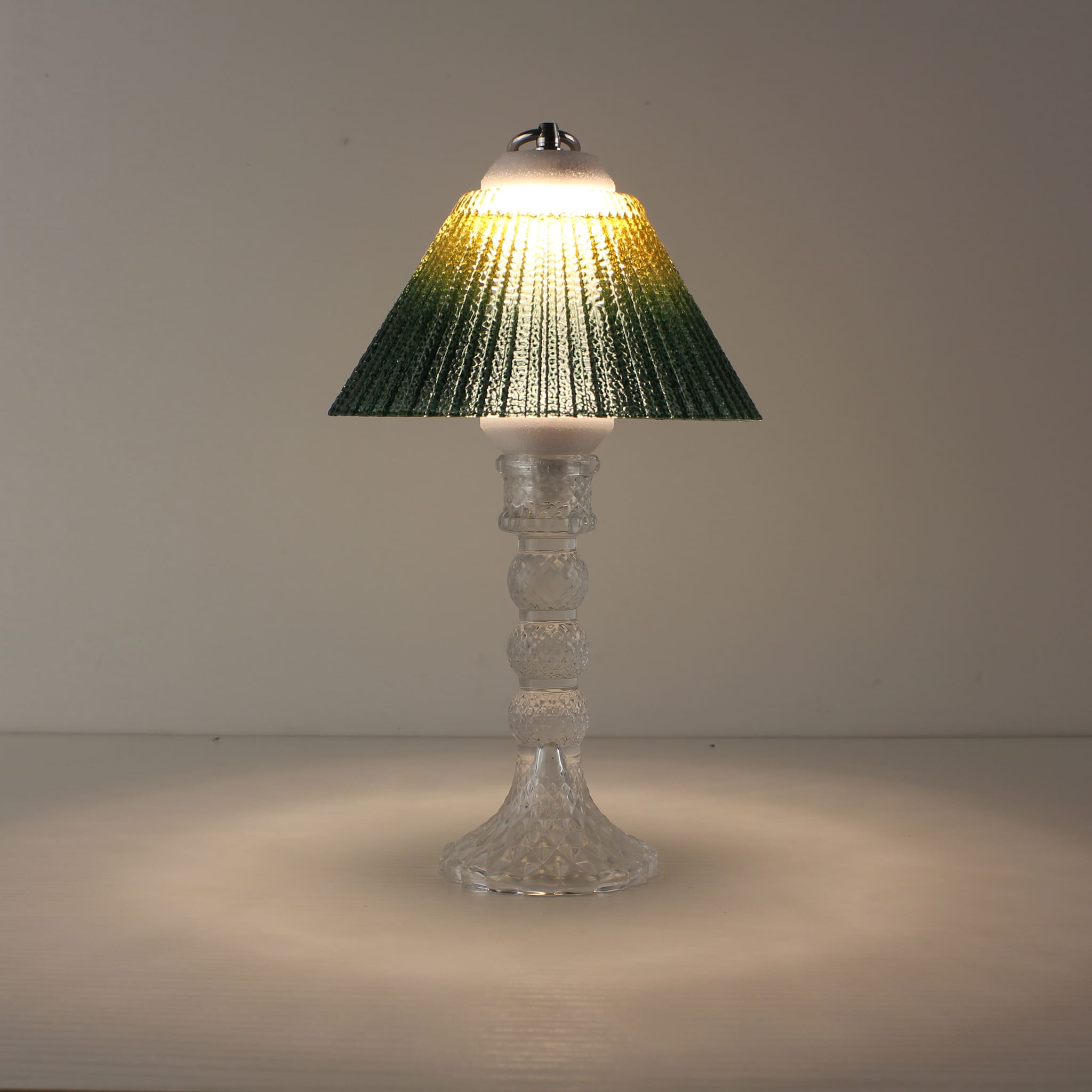 Portable LED lamp (ON) with transparent base and yellow-to-green gradient shade providing warm sunlit illumination.