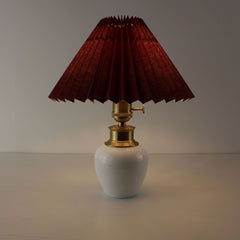 Rechargeable bedside table lamp with a glowing burgundy pleated shade and elegant brass hardware.