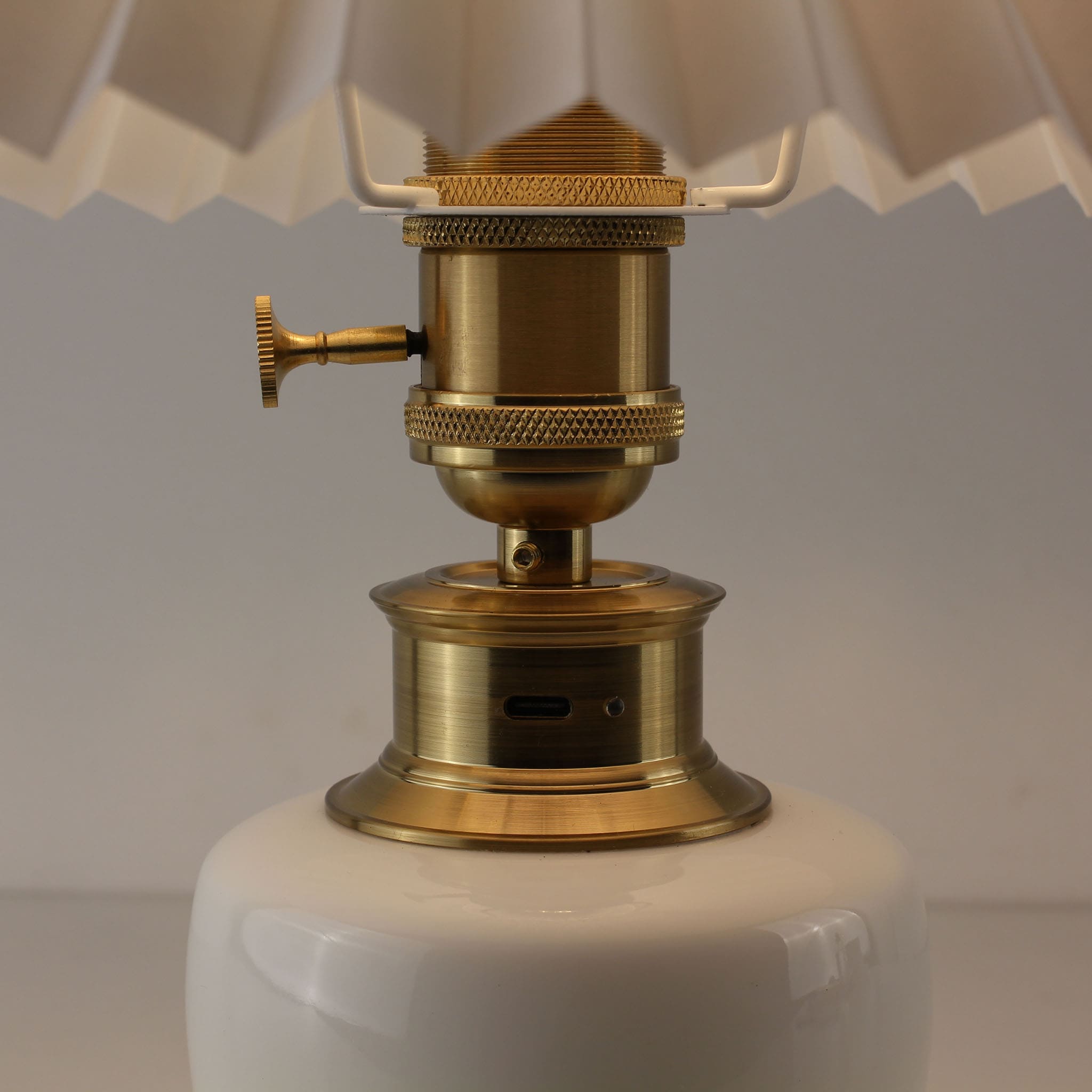 Close-up of the brass base showing the USB-C charging port and power switch of the porcelain lamp.