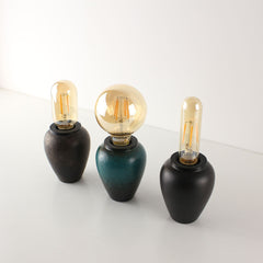 A trio of rechargeable tea caddy lamps in rust, green, and black ceramic glazes, showcasing the artisanal textures and warm vintage lighting