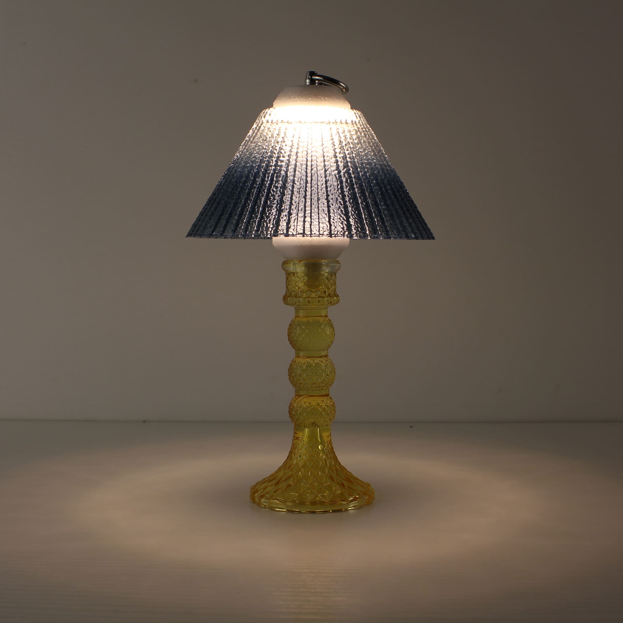 Prism rechargeable cordless lantern (ON) with a yellow faceted glass base and blue gradient shade emitting a warm prismatic glow.