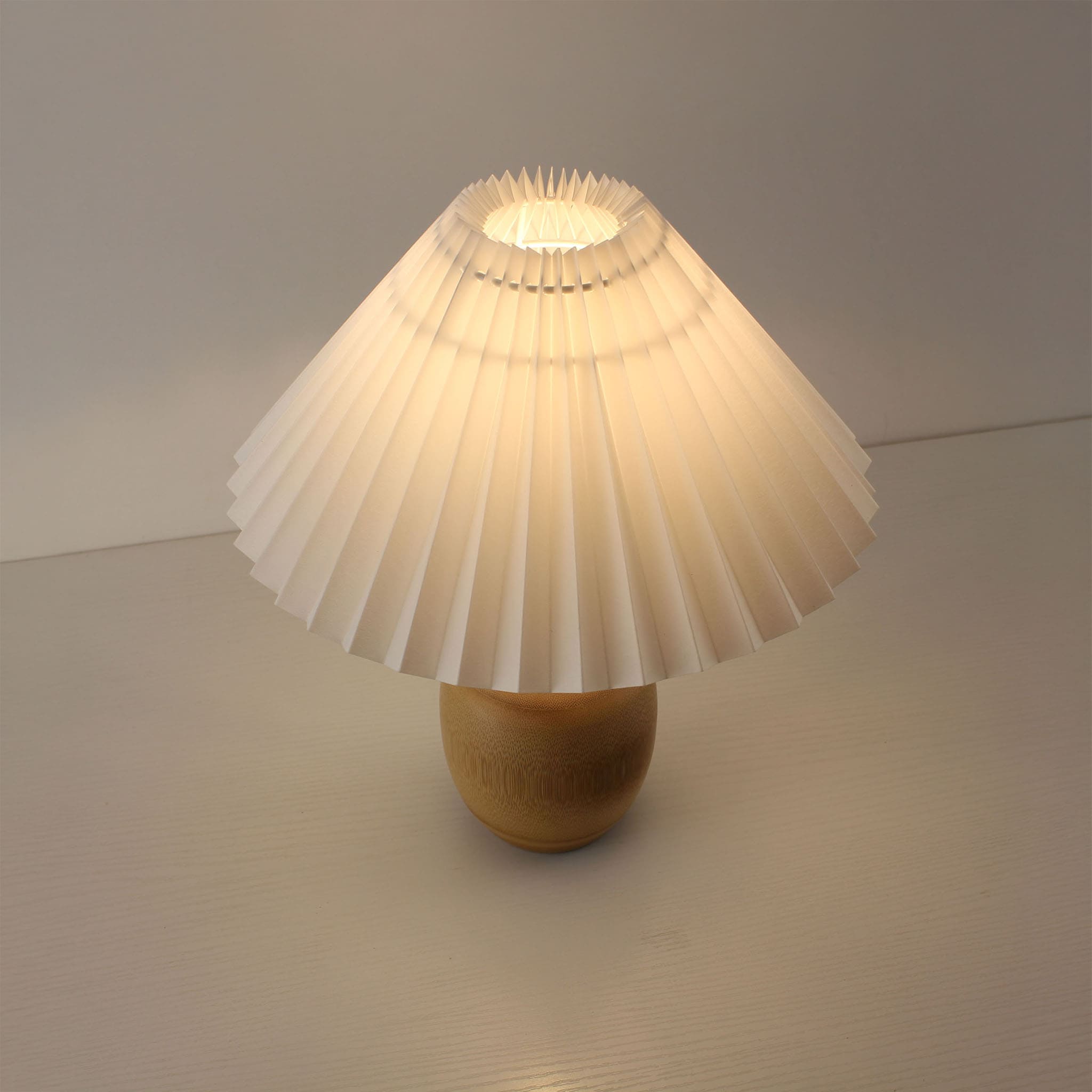 Top-down view of a bamboo cordless lamp with a white pleated shade, showcasing the warm ambient light for modern home decor.