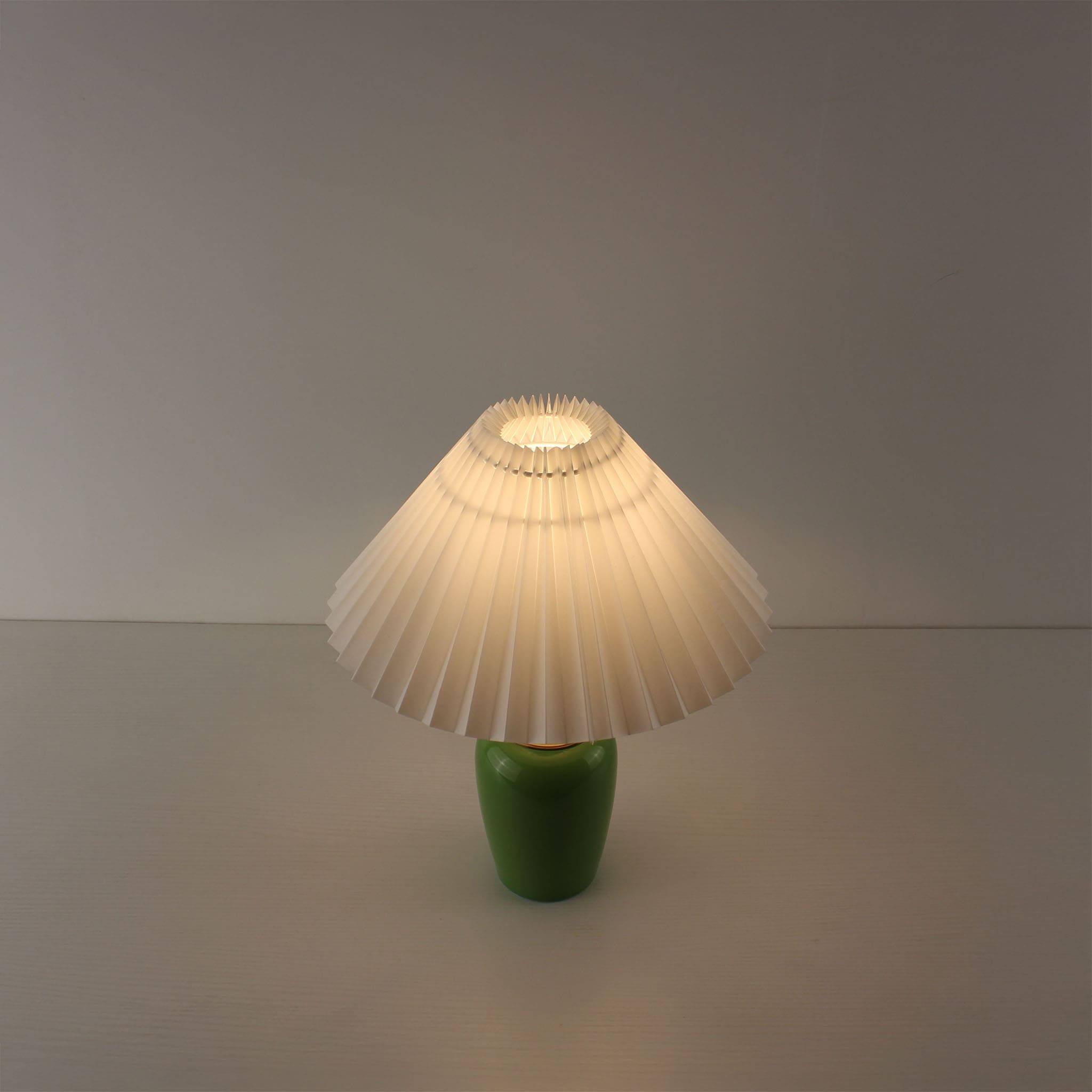 Top-down view of the vintage green ceramic cordless lamp with a white pleated shade glowing, perfect for hallway ambient light.