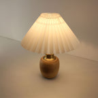 Top down view of a lit pleated shade bamboo lamp, showing warm light diffusion, perfect for cordless outdoor dining or porch.