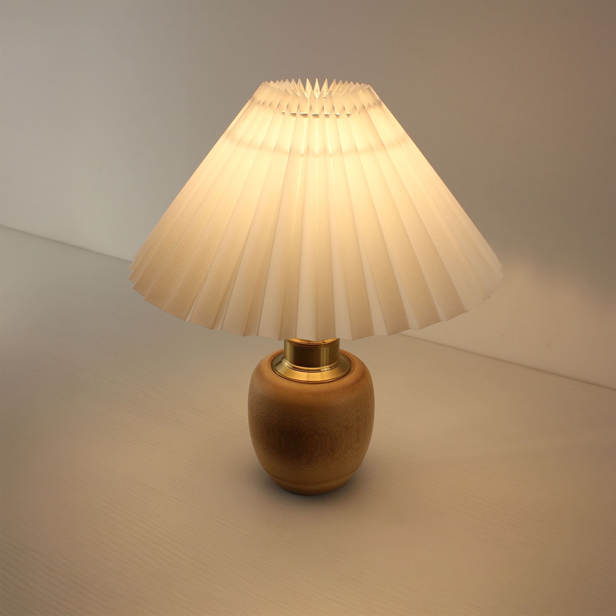 Top down view of a lit pleated shade bamboo lamp, showing warm light diffusion, perfect for cordless outdoor dining or porch.