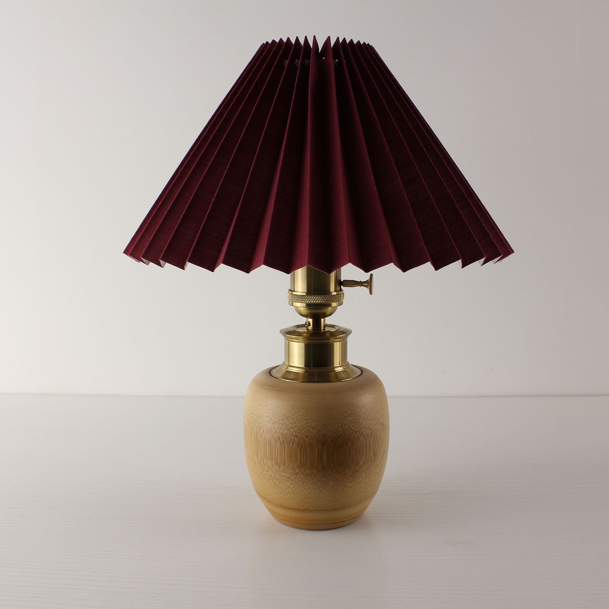 Vintage-inspired wine red pleated shade lamp on bamboo base, wireless rechargeable desk lamp for speakeasy or tavern.