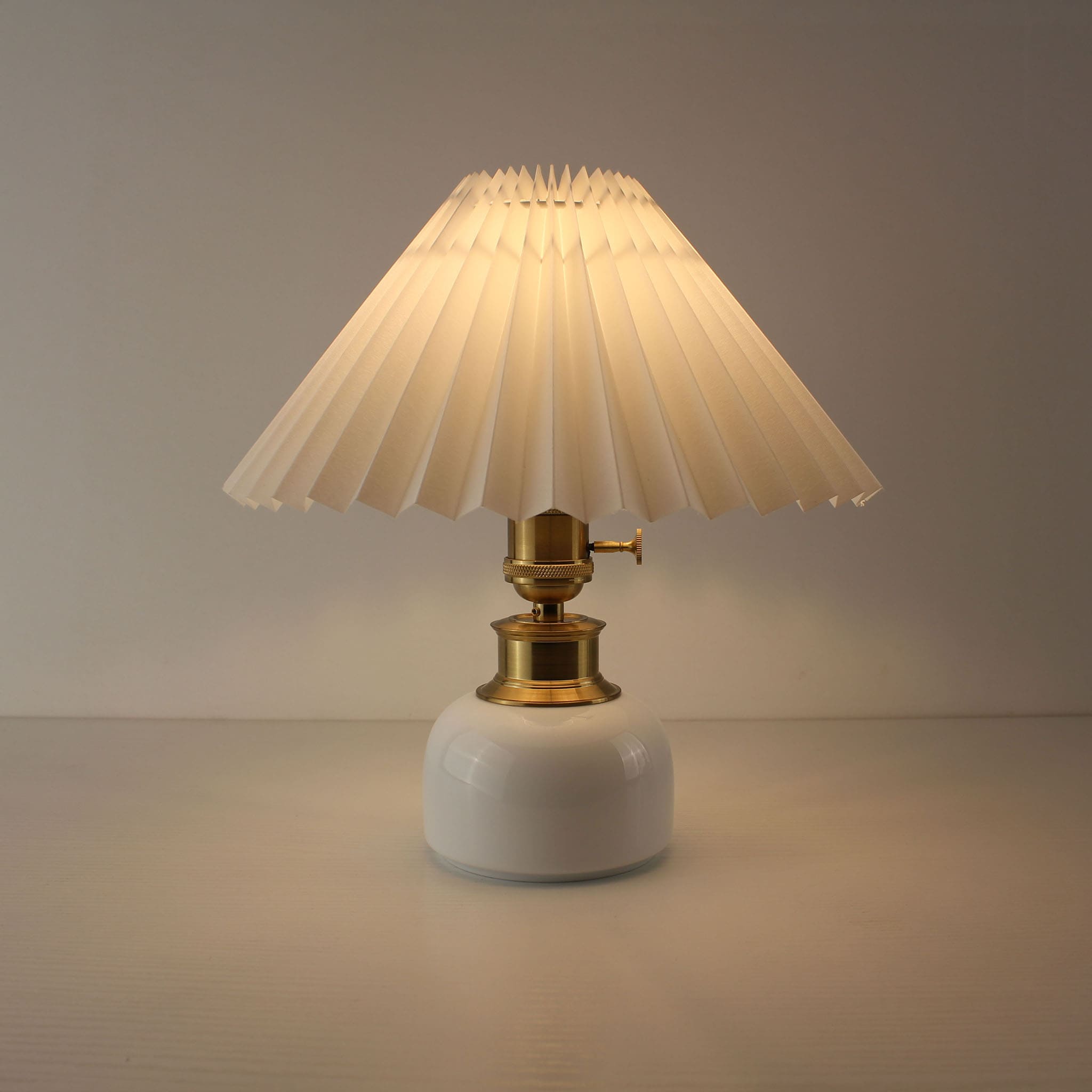 Warm glow rechargeable table lamp with cream pleated shade and white ceramic base for bedside decor.