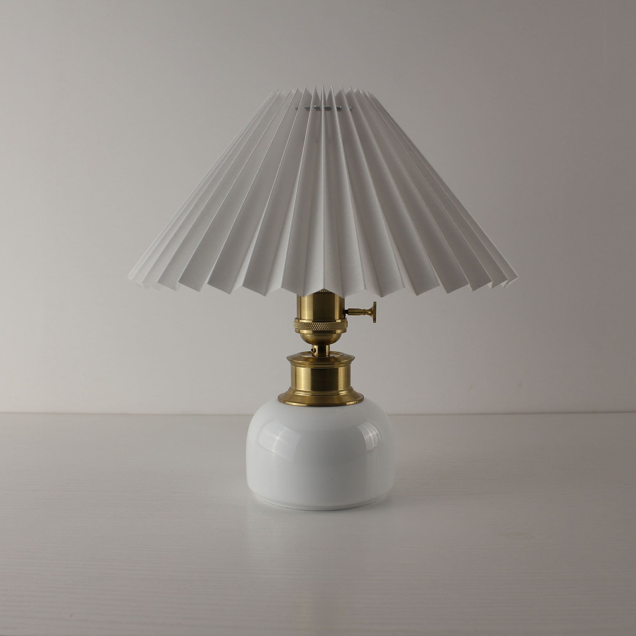 Cordless bistro table lamp with white pleated shade and porcelain base, ideal for commercial cafe lighting.