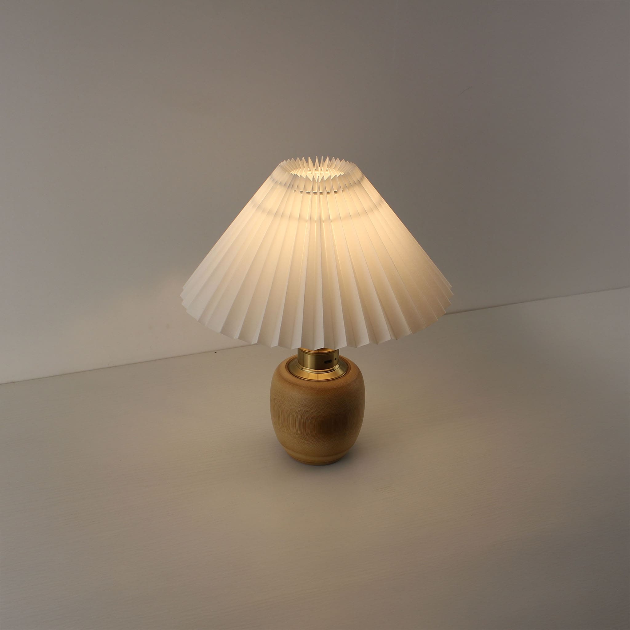 Wide angle shot of a portable bamboo table lamp turned on, highlighting its cordless design and cozy glow for bedside or restaurant tables.