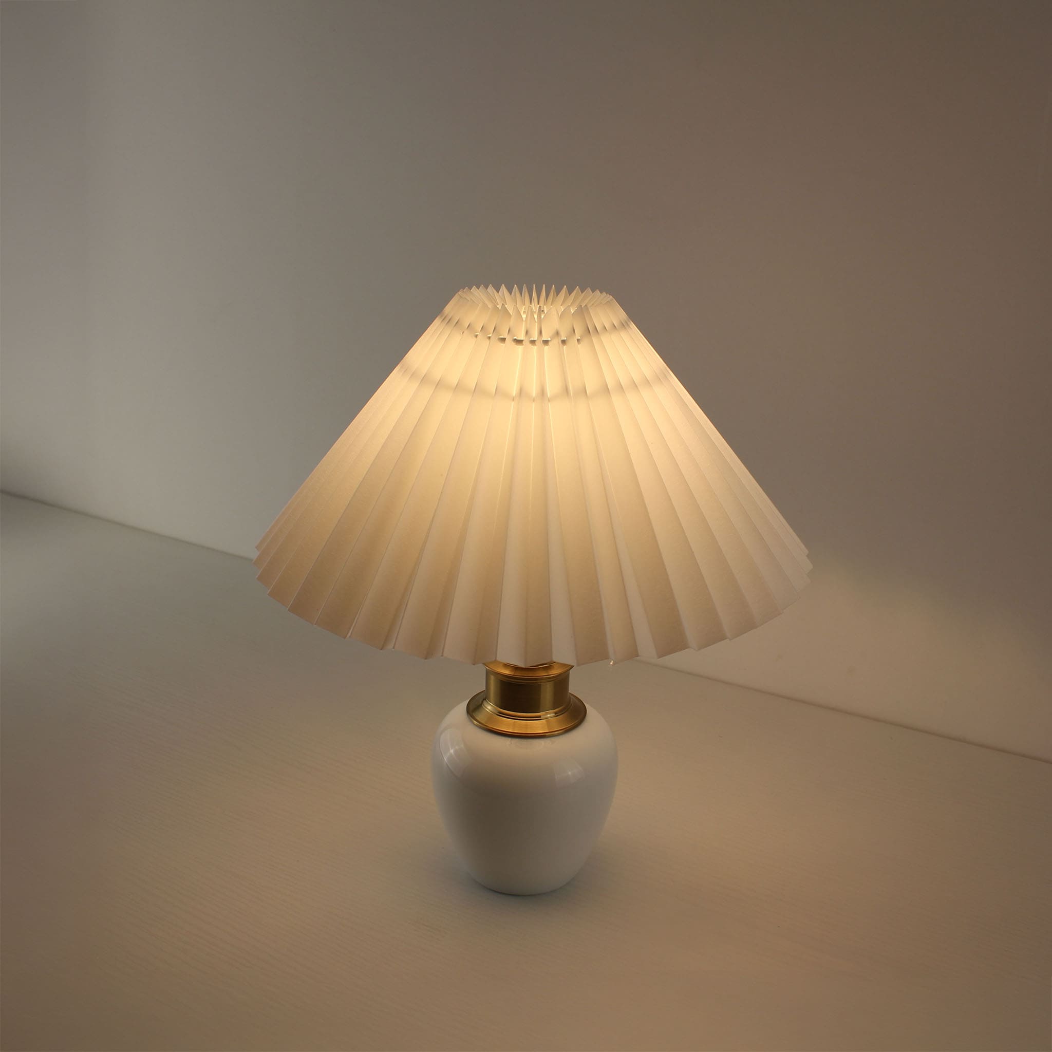 Wireless rechargeable white porcelain lamp with pleated shade on a white desk, perfect for bistro or bar lighting.