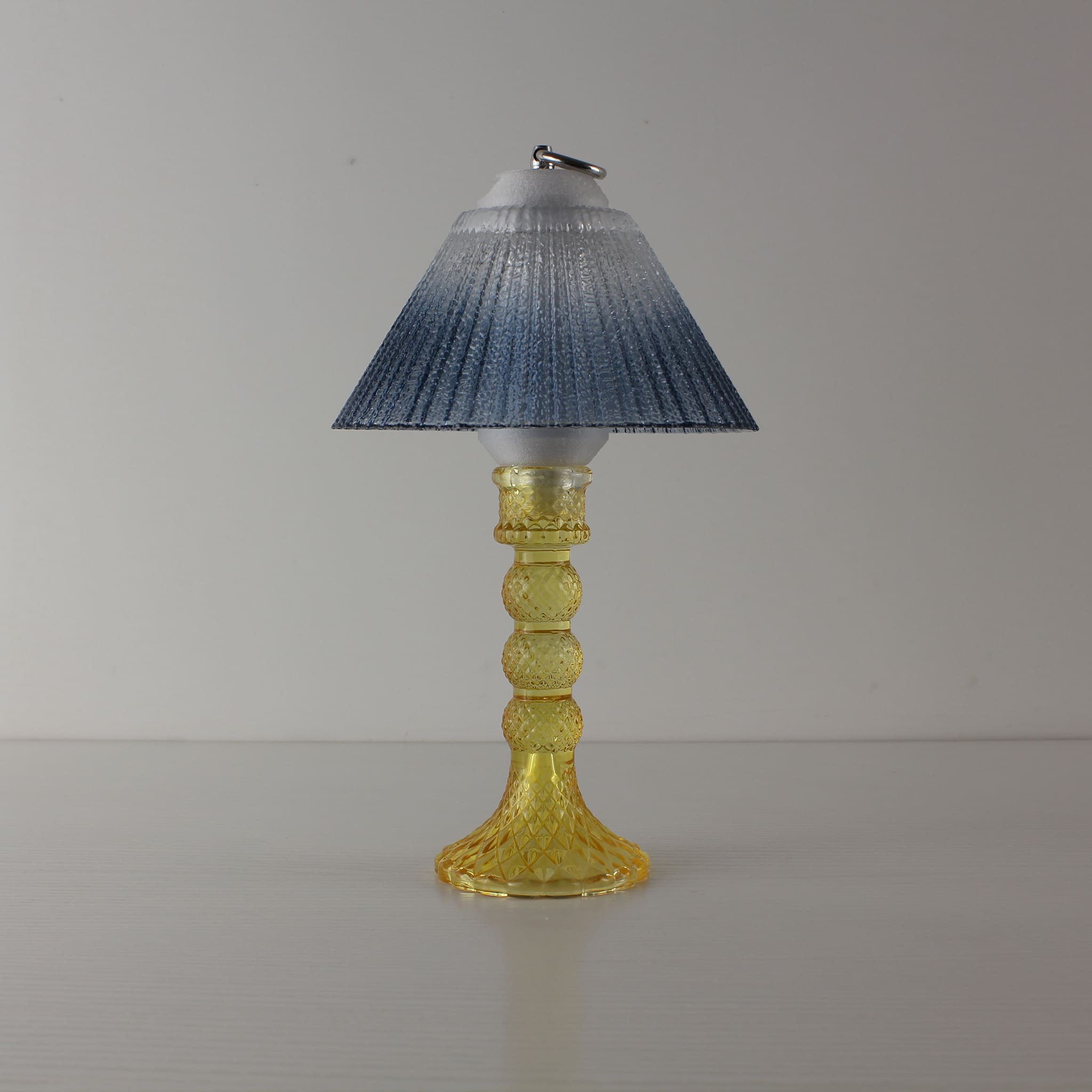 Prism glass centerpiece (OFF) with yellow faceted base and blue gradient shade, showcasing modern clarity in natural daylight.
